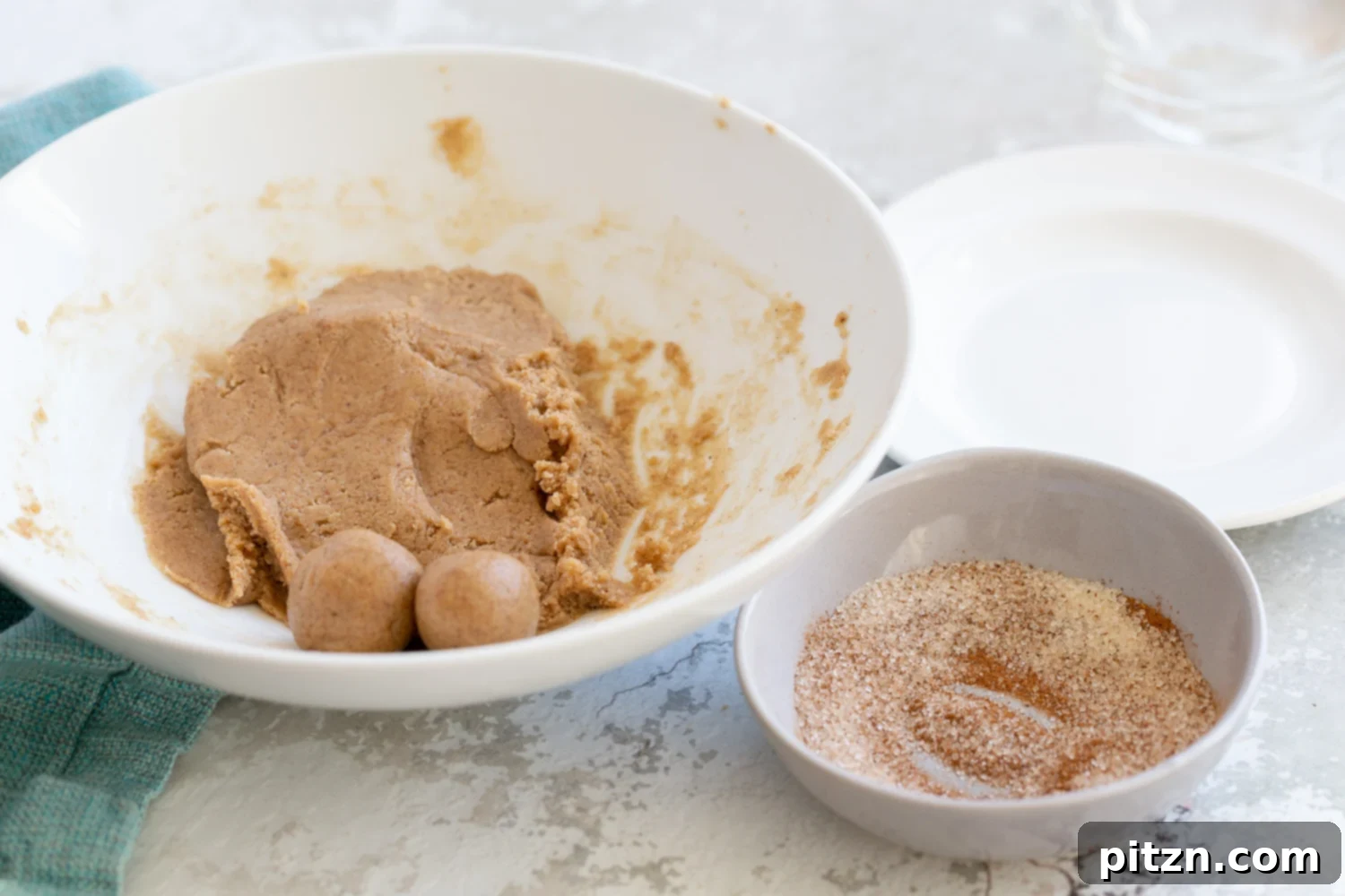 Energy bites Snickerdoodle bites being rolled in a bowl with some cinnamon sugar for coating on the side