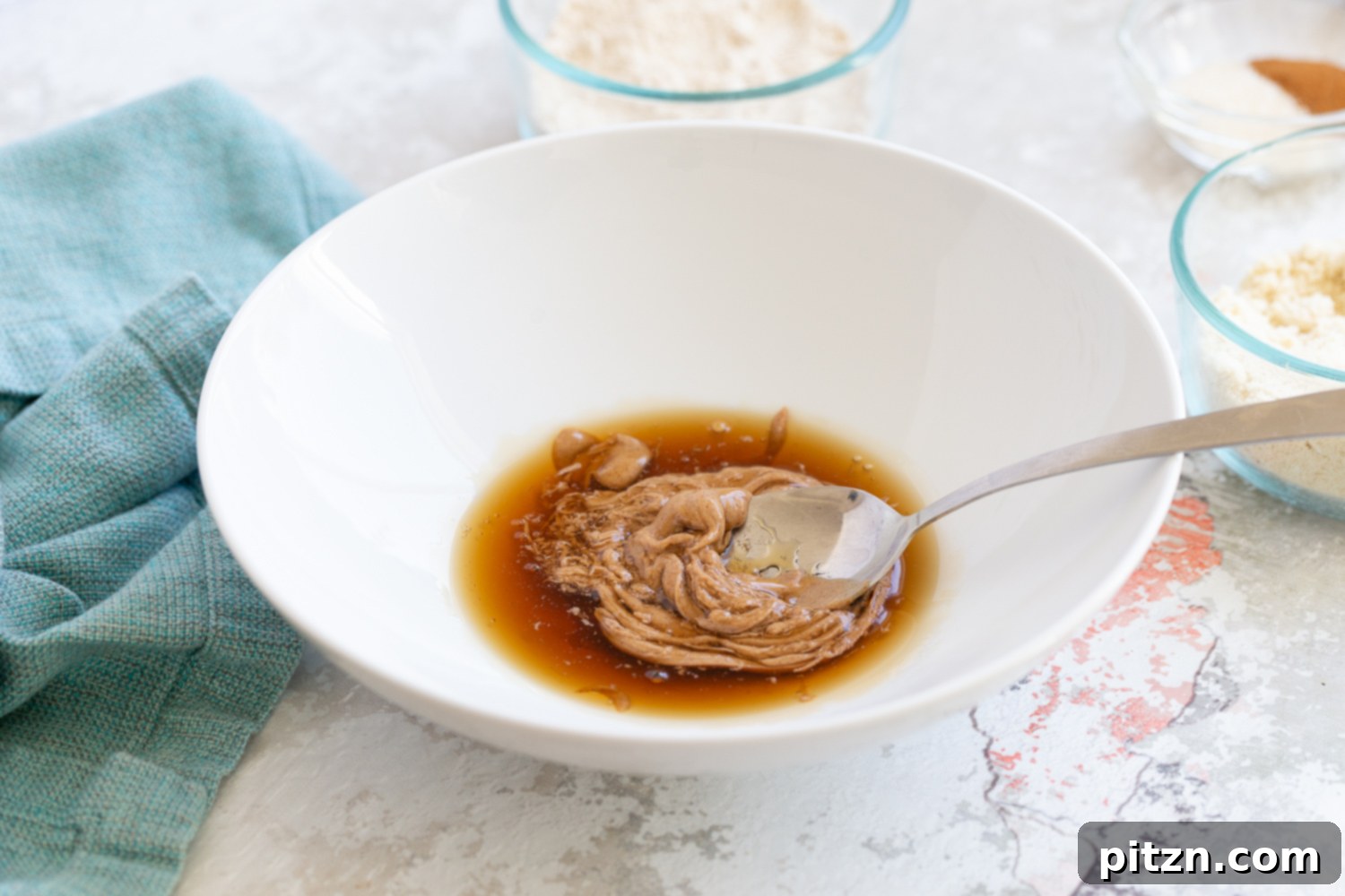 Snickerdoodle bites Maple syrup and nut butter being stirred together in a small bowl