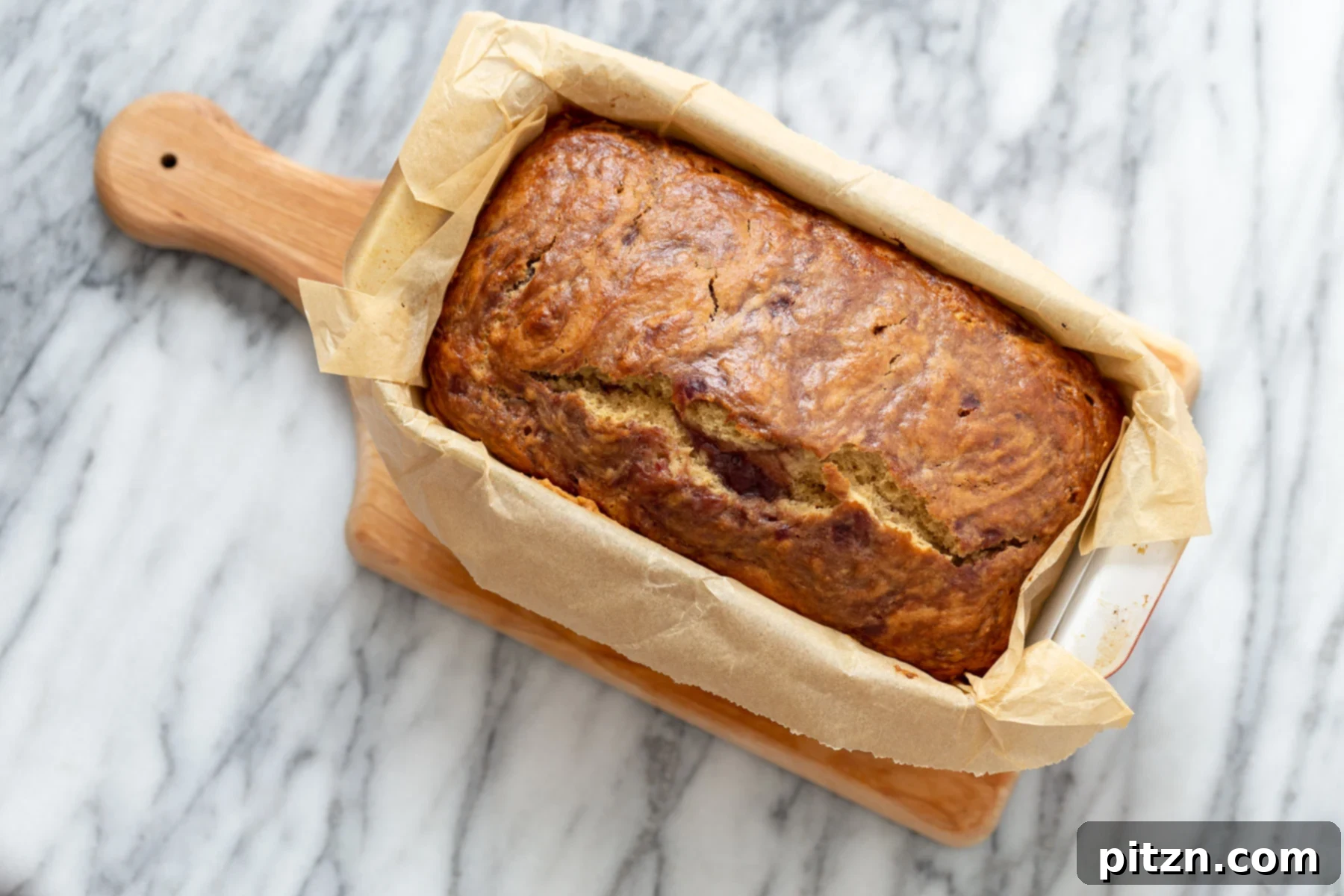 A freshly baked vegan peanut butter and jelly cake, golden brown and still in its loaf pan, emanating a comforting aroma.