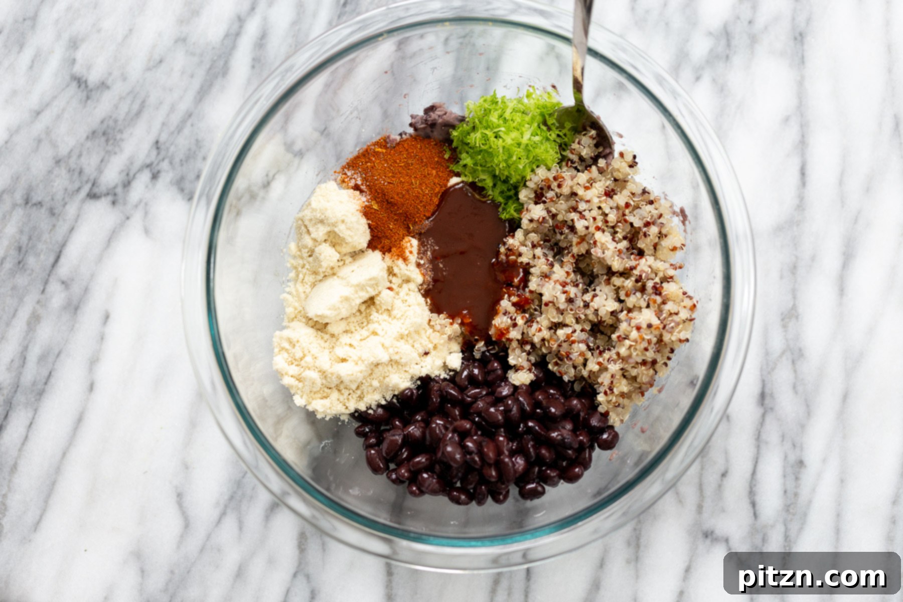 Mixed Quinoa Black Bean Ingredients All the vibrant ingredients for making delicious black bean quinoa patties, perfectly gathered and mixed in a clear glass bowl.