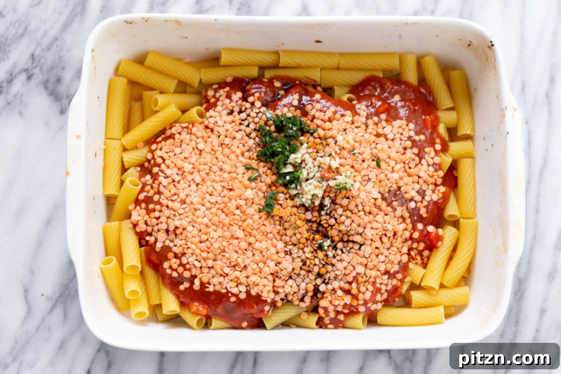 baked rigatoni overhead shot of casserole dish with raw pasta, marinara and red lentils