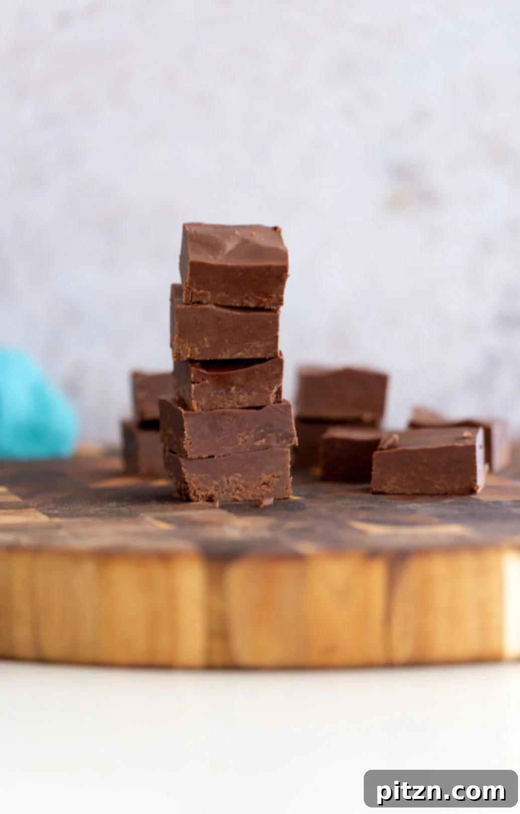 A beautiful stack of easy healthy vegan chocolate fudge pieces arranged on a rustic wooden board, emphasizing its homemade appeal and tempting chocolatey goodness.