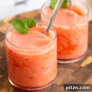 Two glasses of vegan strawberry lemonade slushie adorned with fresh mint leaves, ready to be enjoyed.