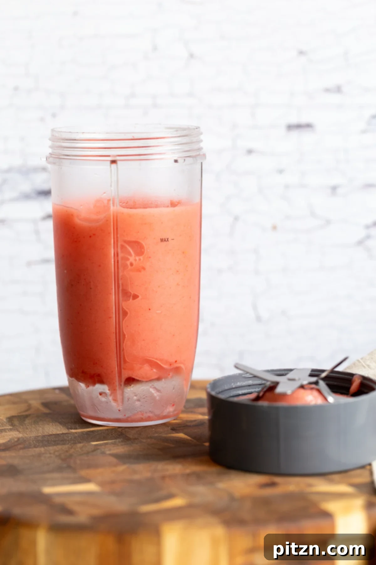 A vibrant, swirling frozen strawberry lemonade slushie actively blending inside a high-speed blender, showcasing its smooth, icy texture.