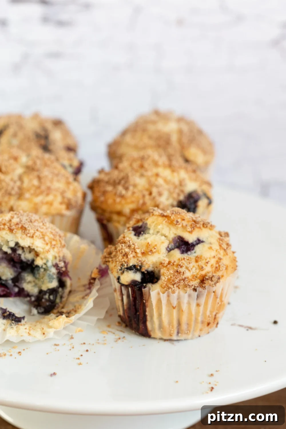 Summer Harvest: Your Guide to Seasonal Eats and Vegan Delights 10 Easy Vegan Blueberry Muffins with Streusel topping on a cake stand, highlighting fresh berries in baked goods for summer.