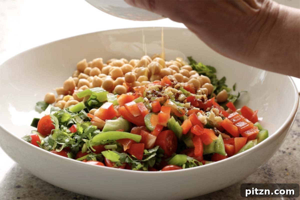 Balela Fresh Herby Chickpea and Garden Delight 10 Tossing the Balela salad with its dressing in a large bowl, highlighting the vibrant colors and fresh ingredients.