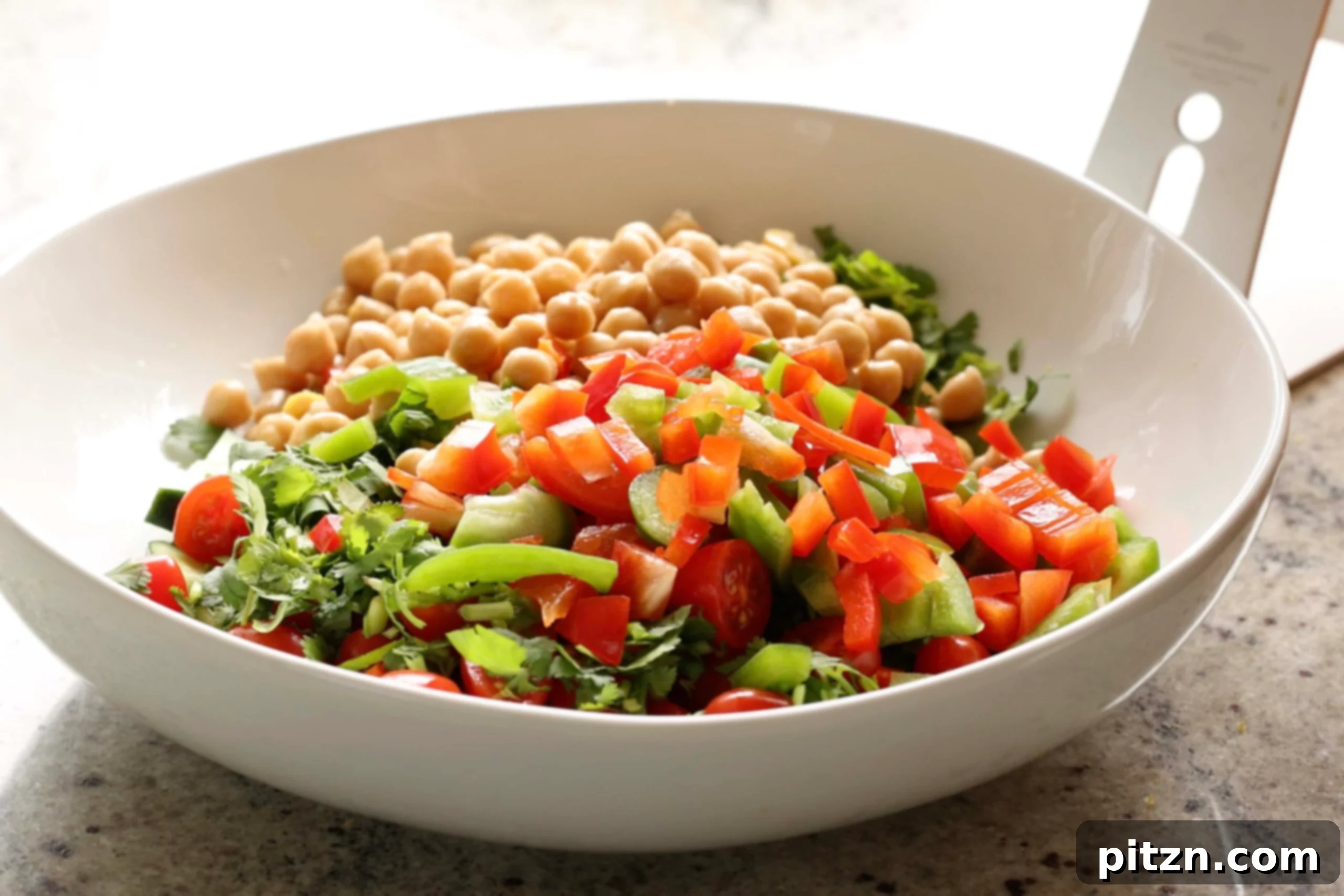 Balela Fresh Herby Chickpea and Garden Delight 8 Adding chickpeas to a bowl with other salad ingredients, demonstrating the first step in preparation.