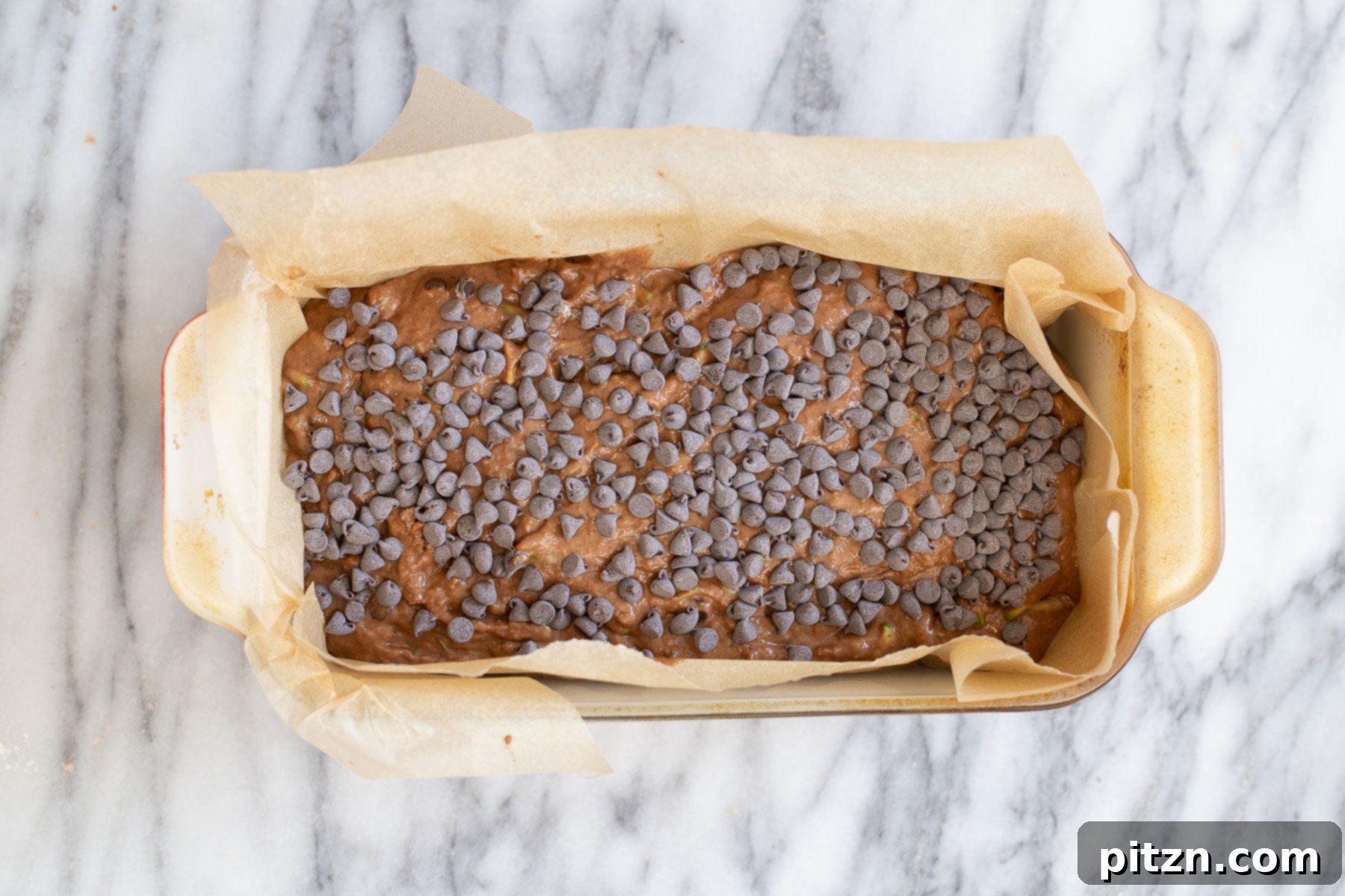 Raw, unbaked vegan chocolate zucchini bread batter, beautifully sprinkled with chocolate chips, ready to go into the oven.