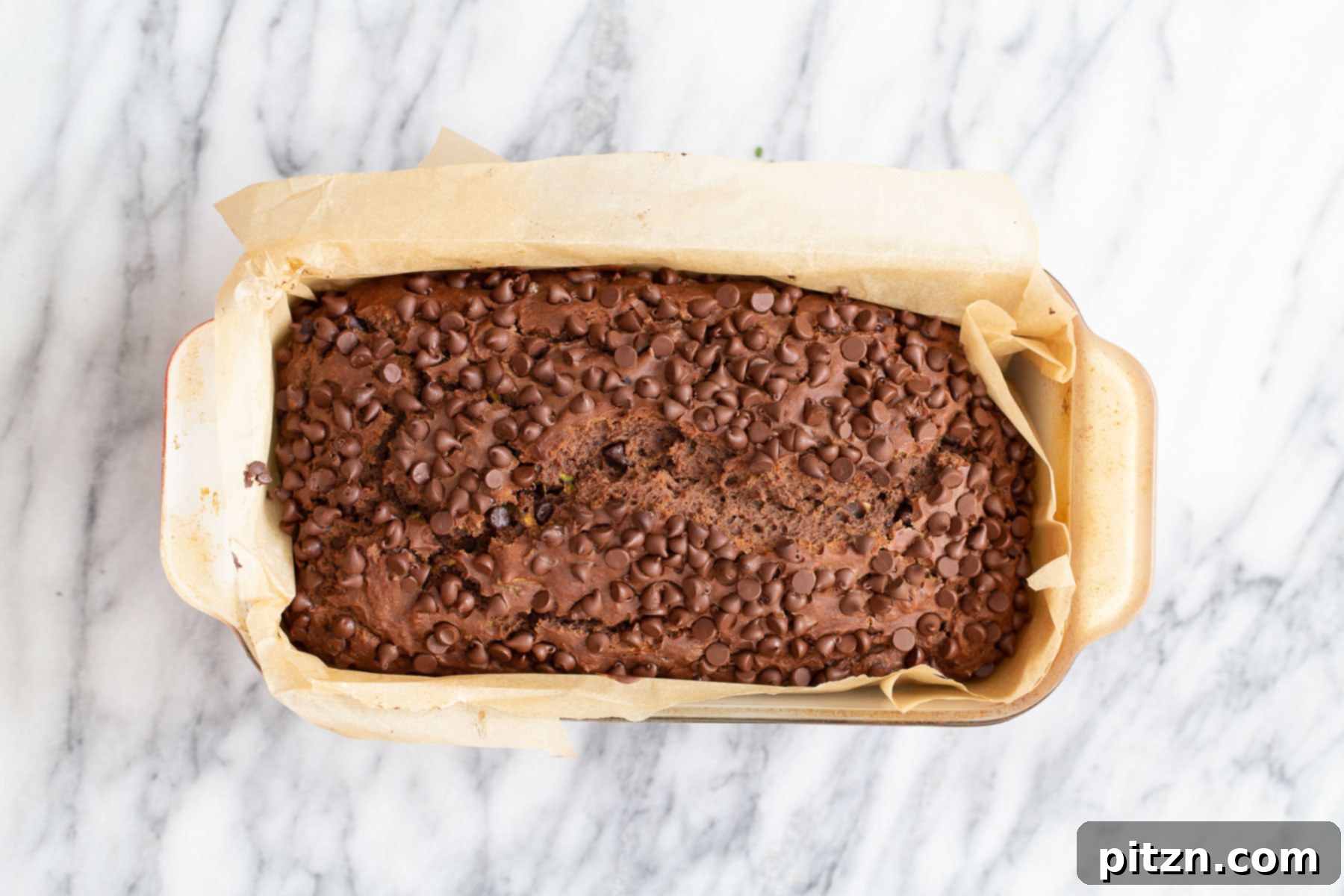 A freshly baked loaf of vegan chocolate zucchini bread, golden brown and enticing, cooling on a wire rack.