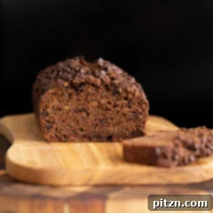 Close-up of a slice of vegan chocolate zucchini bread with a rich chocolate crumb and visible chocolate chips.