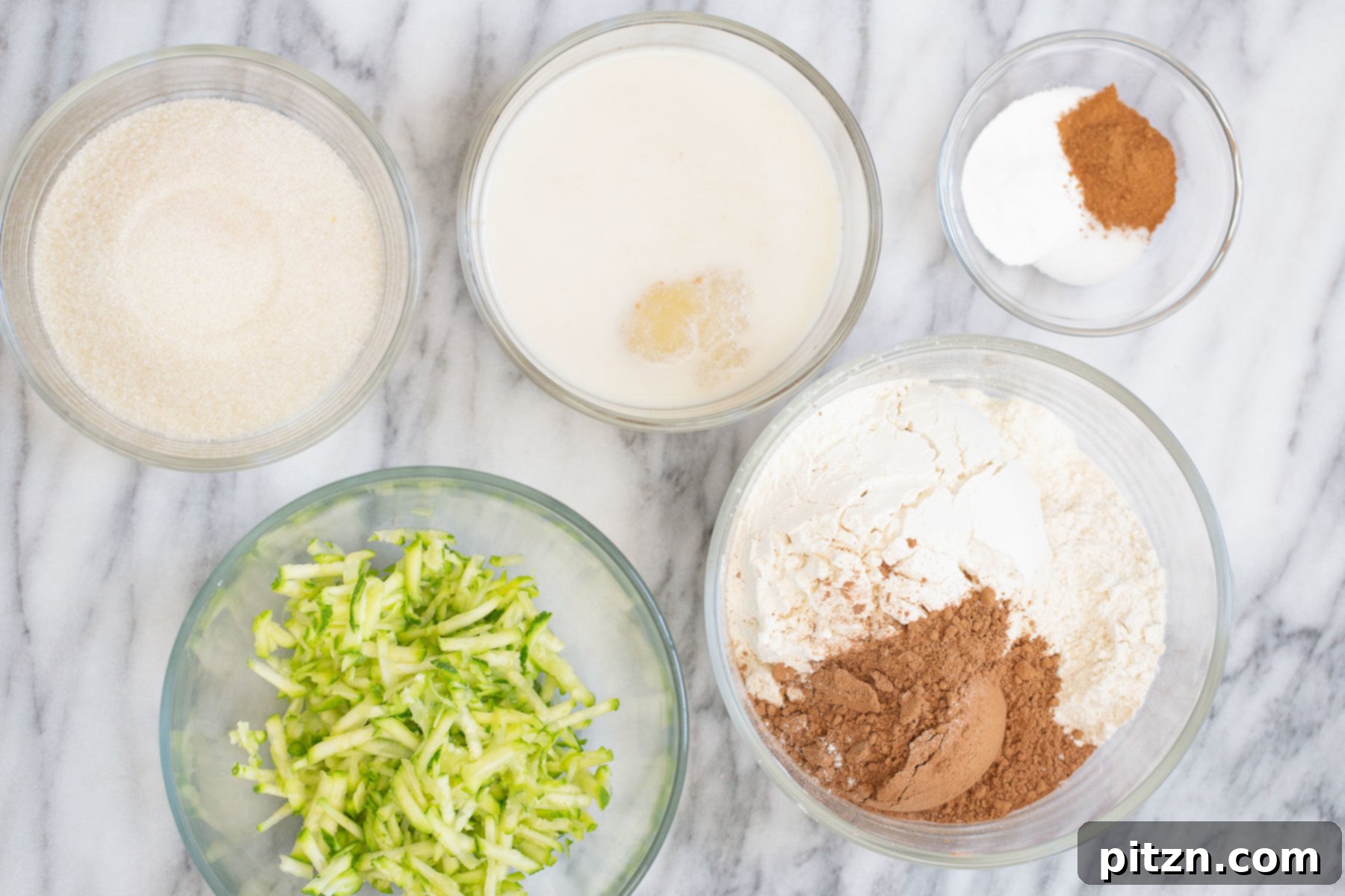 Overhead shot of all the dry and wet ingredients arranged for making vegan chocolate zucchini bread in separate bowls, ready for mixing.