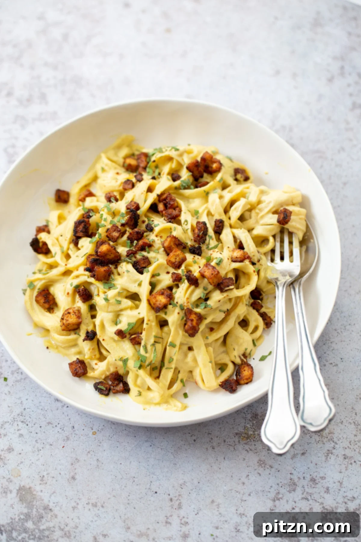 close up of a plate of vegan butternut squash pasta carbonara served with baked tofu