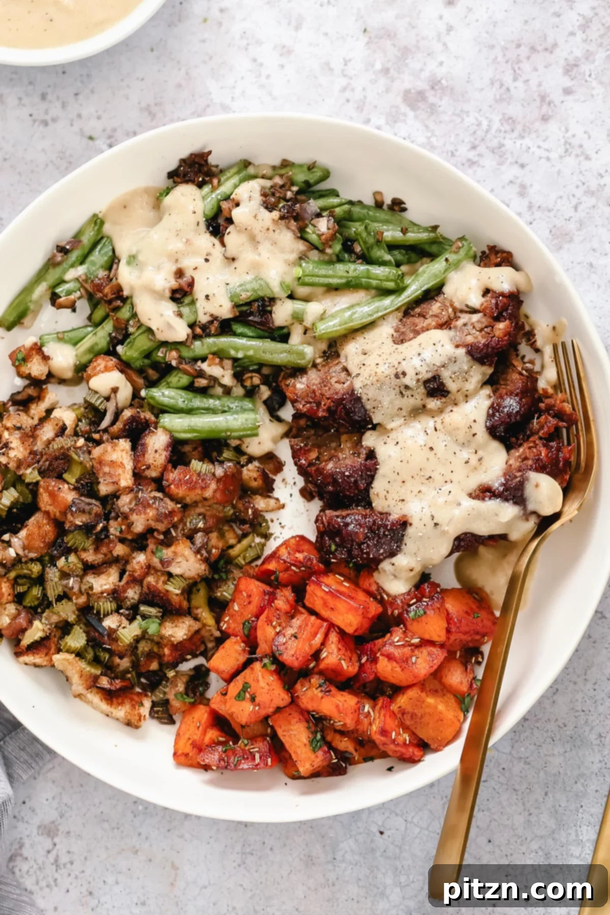 Stress-Free Vegan Thanksgiving Sheet Pan Dinner Overhead shot of a vibrant vegan sheet pan Thanksgiving dinner, beautifully arranged on a plate with a golden-brown lentil loaf and colorful sides.