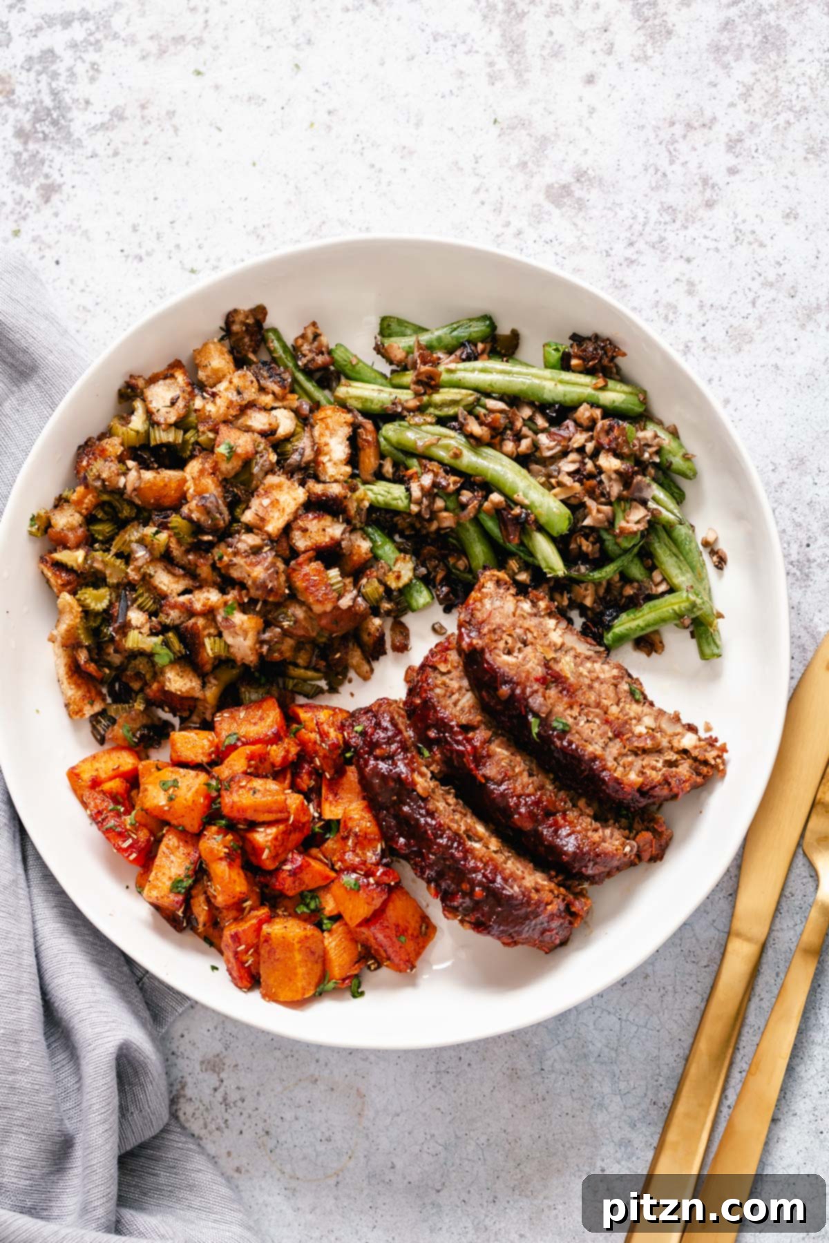 Vegan Thanksgiving Sheet Pan Dinner Components Close-up of a plate showcasing a slice of vegan lentil loaf, alongside vibrant roasted sweet potatoes and fresh green beans, all part of the Thanksgiving sheet pan meal.