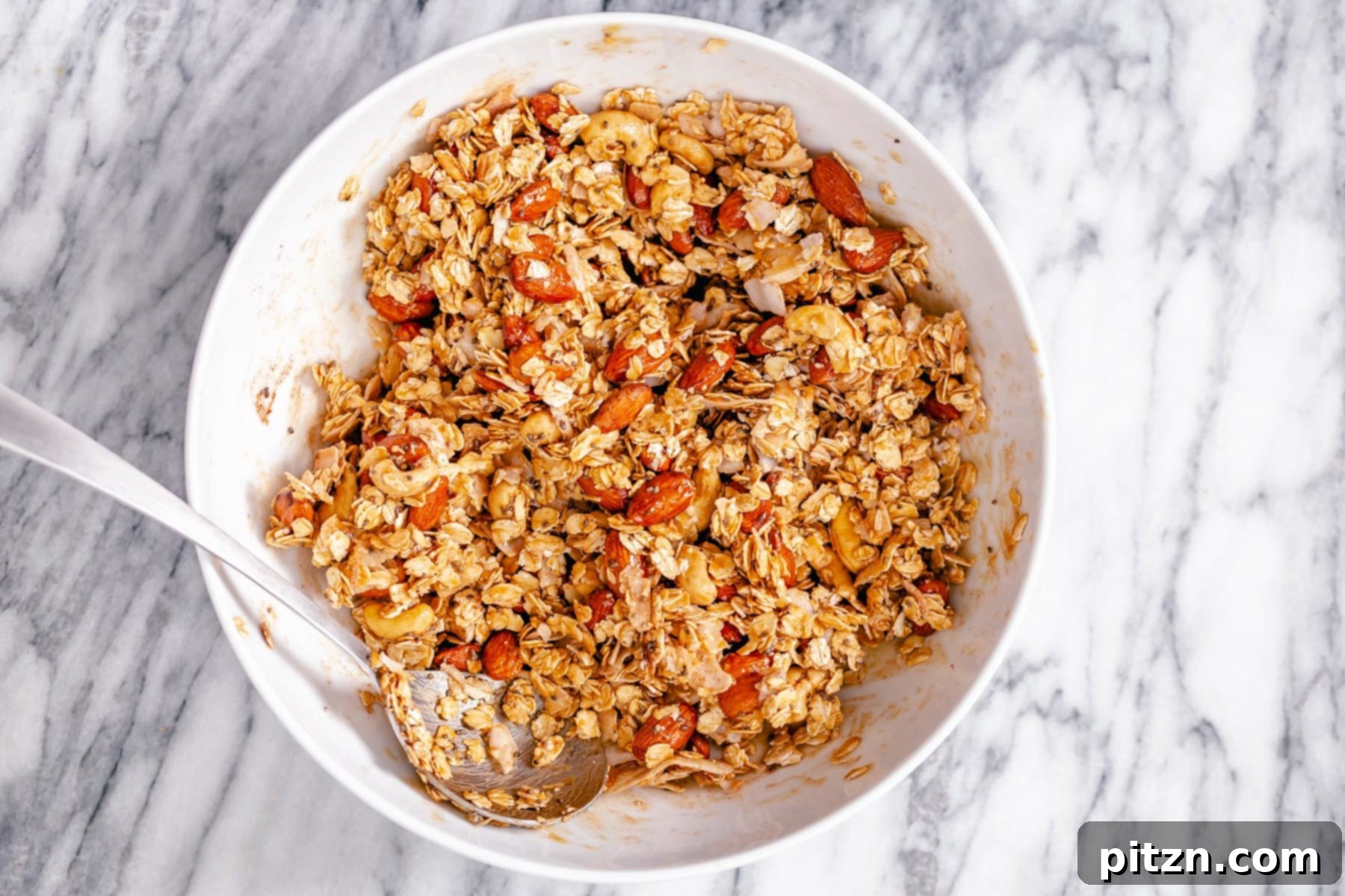 Coating Granola Mixture Almond coconut granola being mixed in a small white bowl
