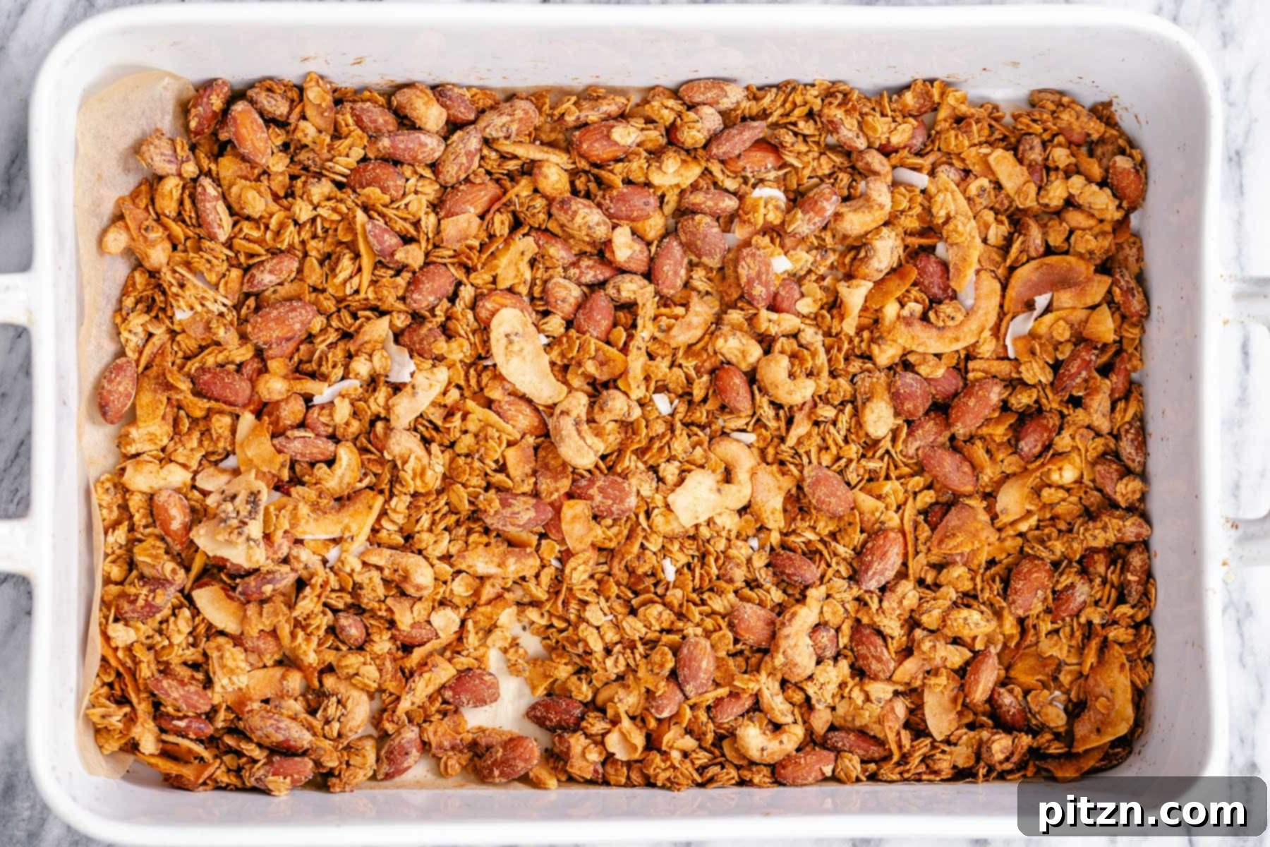 Baked Granola Cooling A white casserole dish filled with baked vegan granola