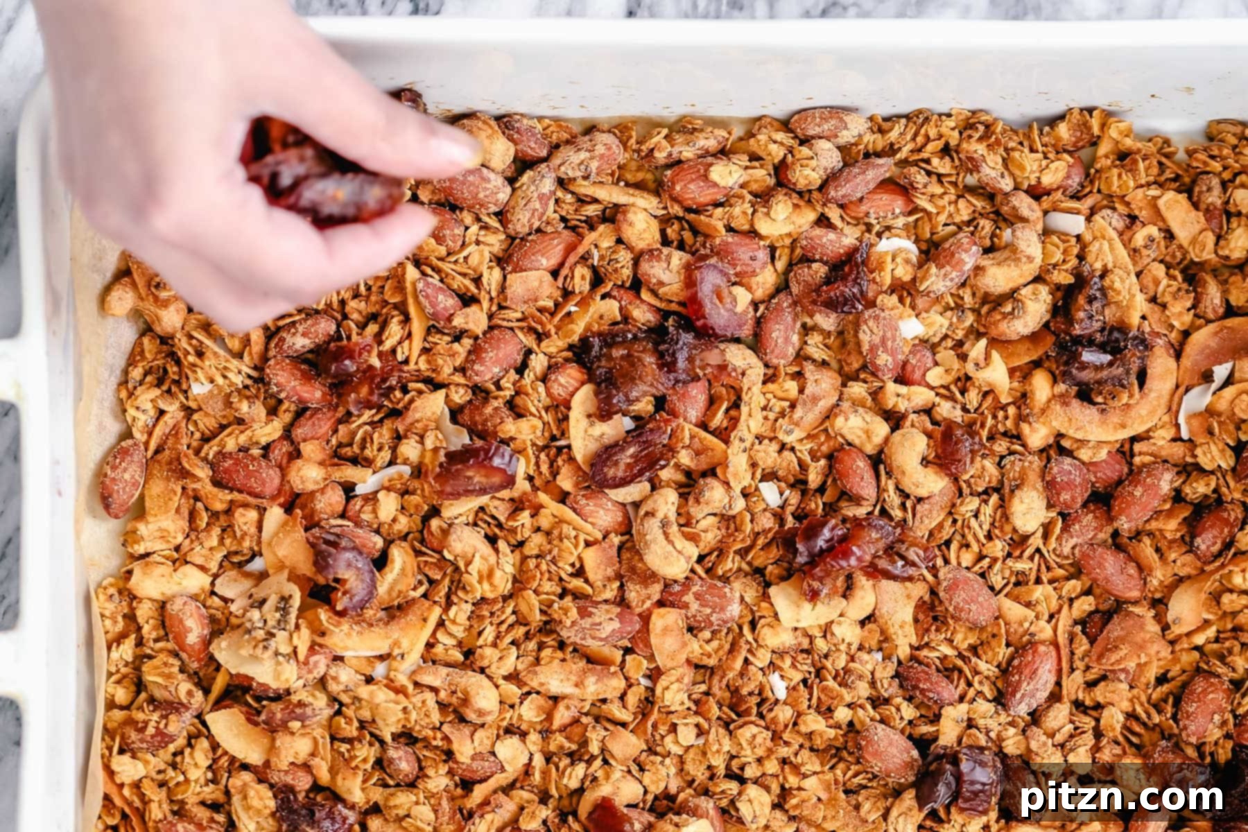 Granola Baking Progress Baked vegan granola being spread out in a casserole dish
