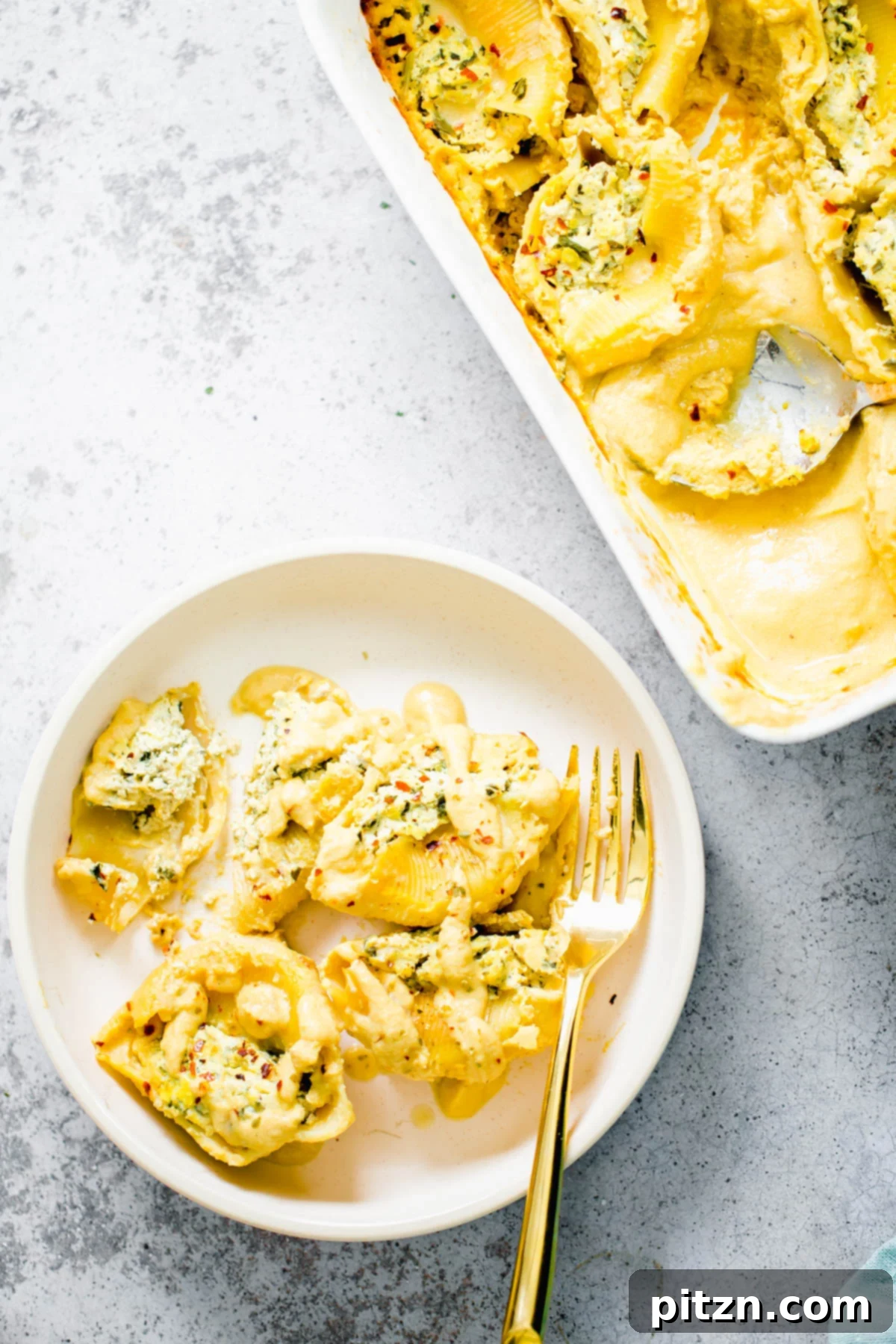 Vegan Stuffed Shells with Butternut Squash Alfredo Overhead shot of vegan stuffed shells with creamy tofu ricotta and vibrant butternut squash alfredo sauce, garnished with fresh herbs.