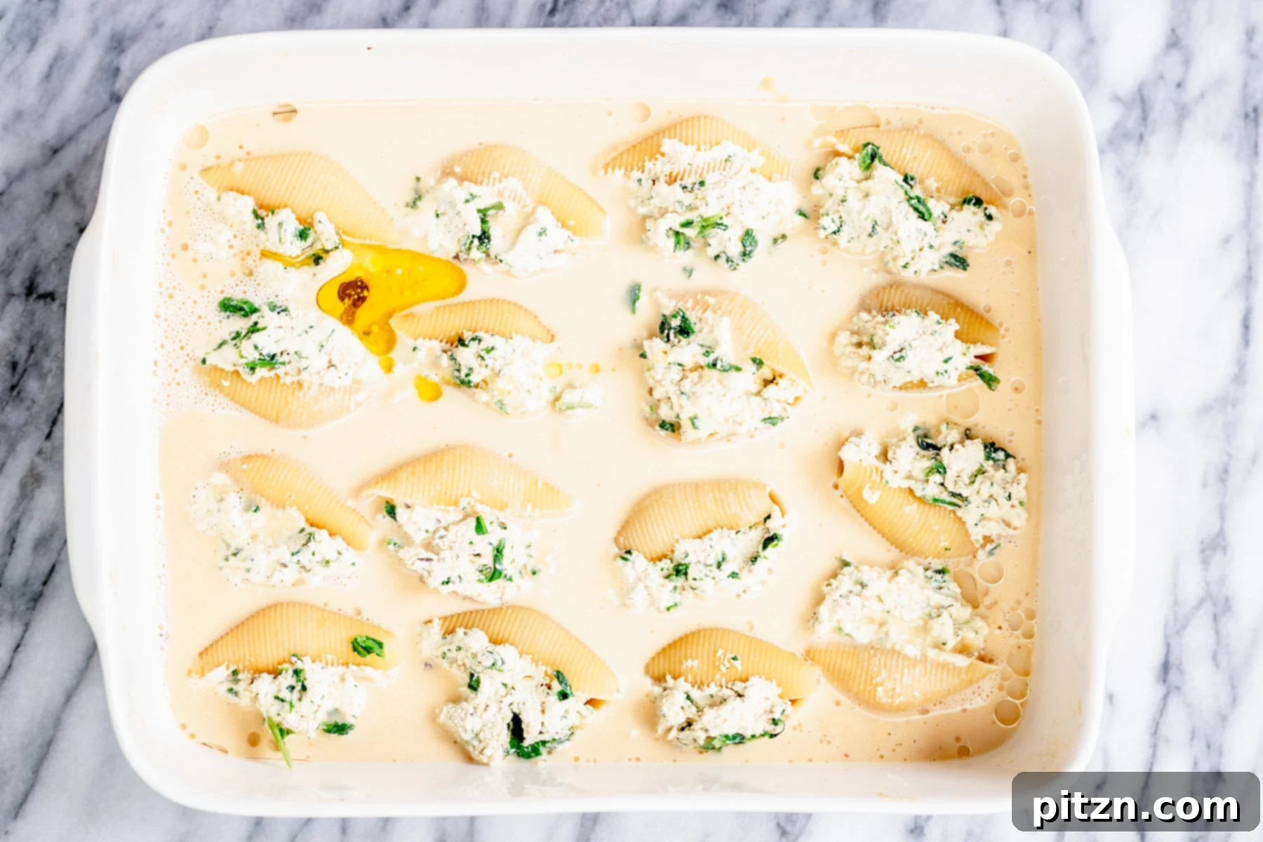 Butternut Squash Stuffed Shells Ready for Baking Overhead shot of a casserole dish with vegan stuffed shells submerged in butternut squash alfredo sauce before baking.
