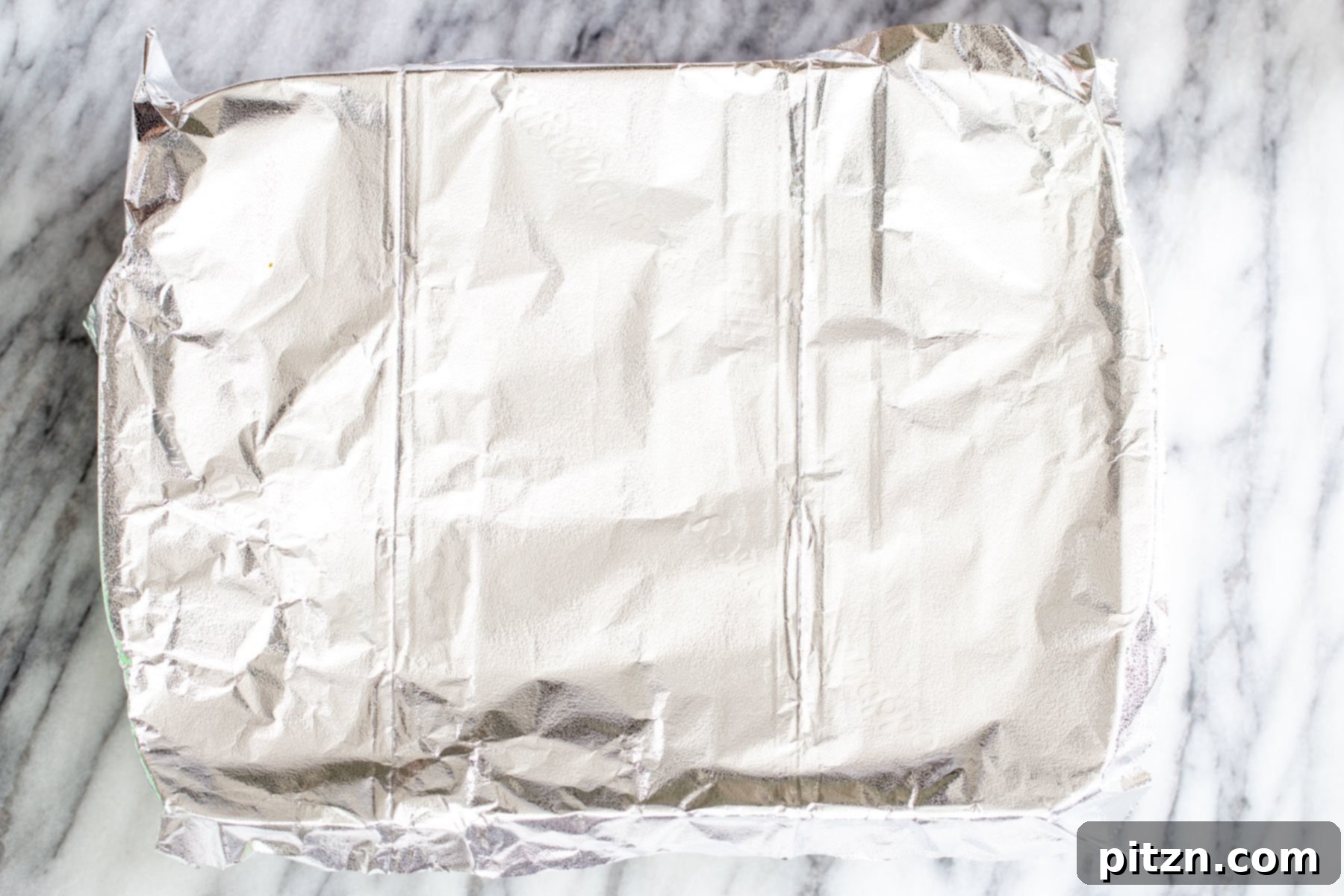 Covered Casserole Dish A casserole dish covered tightly with aluminum foil, prepared for baking.