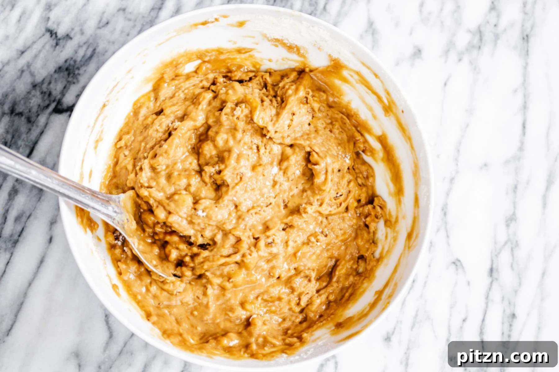 Smooth vegan gingerbread banana bread batter in a white mixing bowl, ready for the loaf pan.