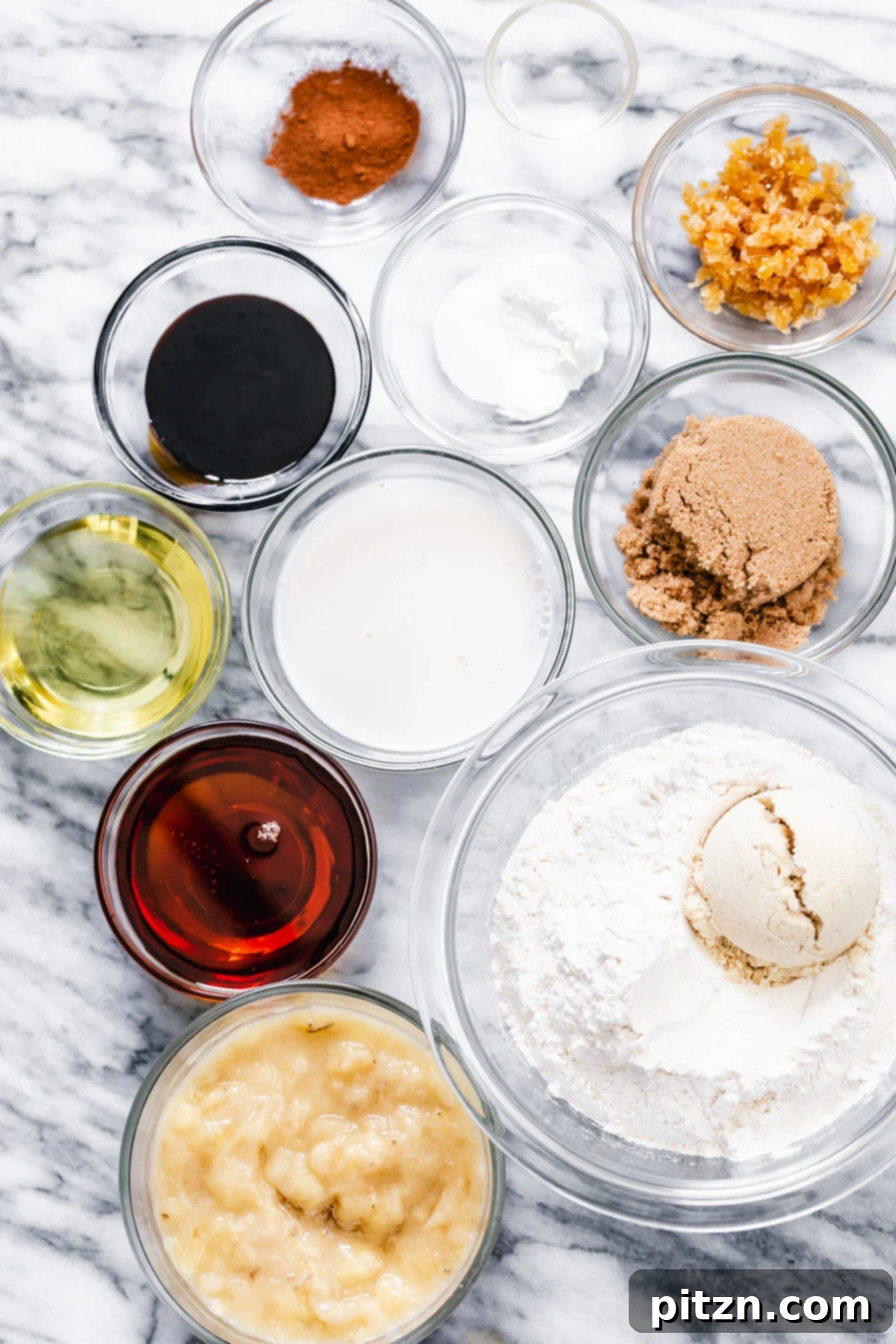 Overhead shot of all the essential ingredients laid out for making vegan gingerbread banana bread, including mashed bananas, spices, and flours.