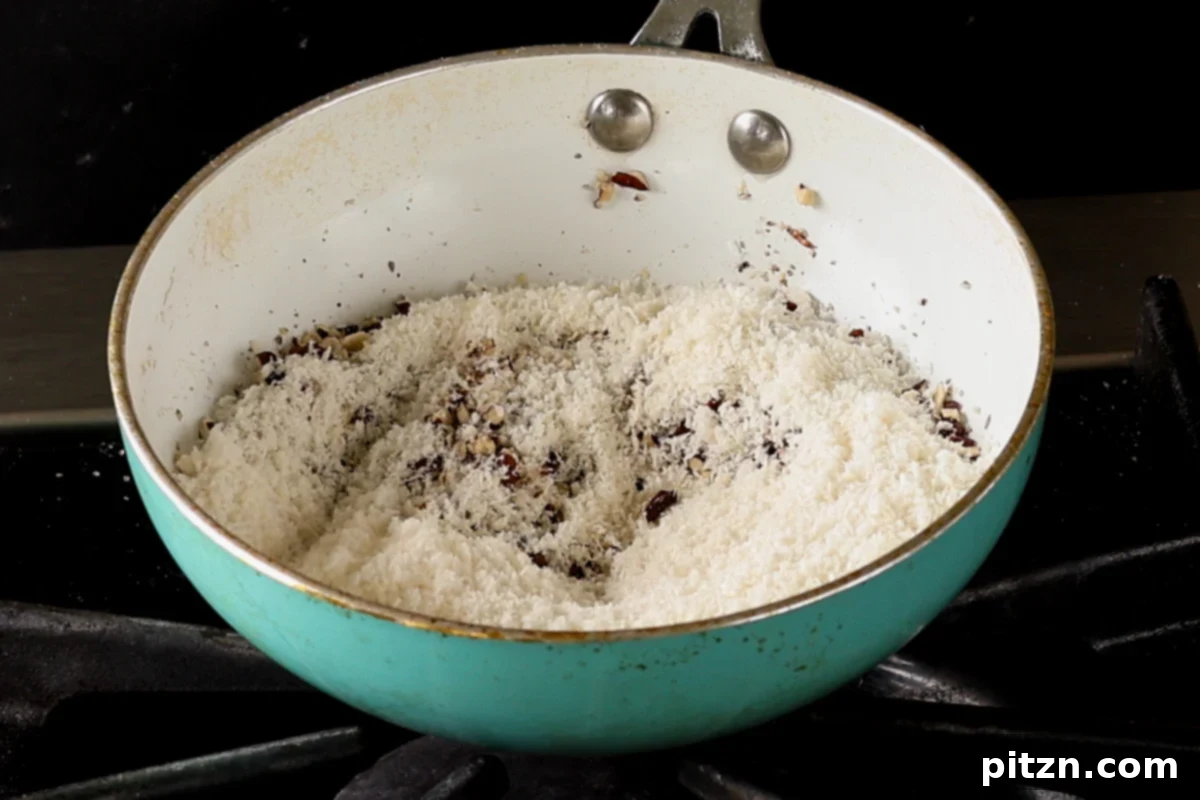 Shredded coconut being added to the toasted pecans in the skillet, preparing for further cooking to create the filling.