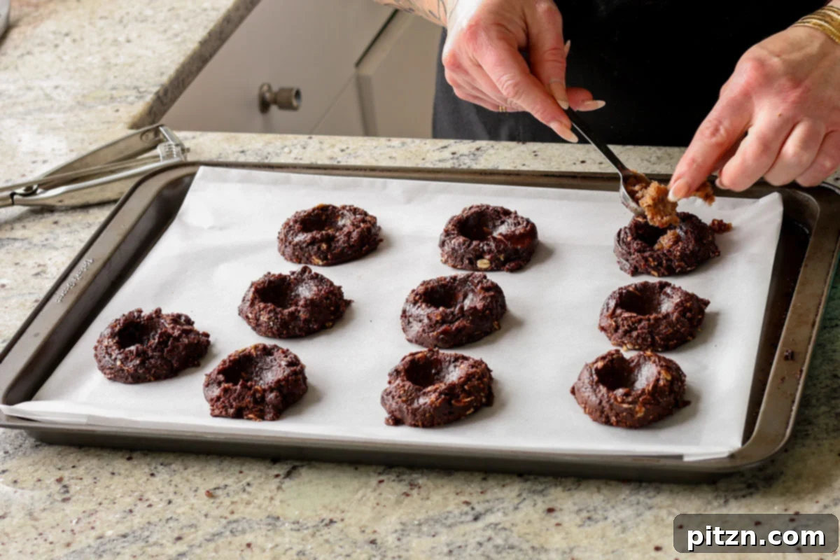 Creating wells in the centers of the unbaked German chocolate cookies using a measuring spoon, ready for the filling.