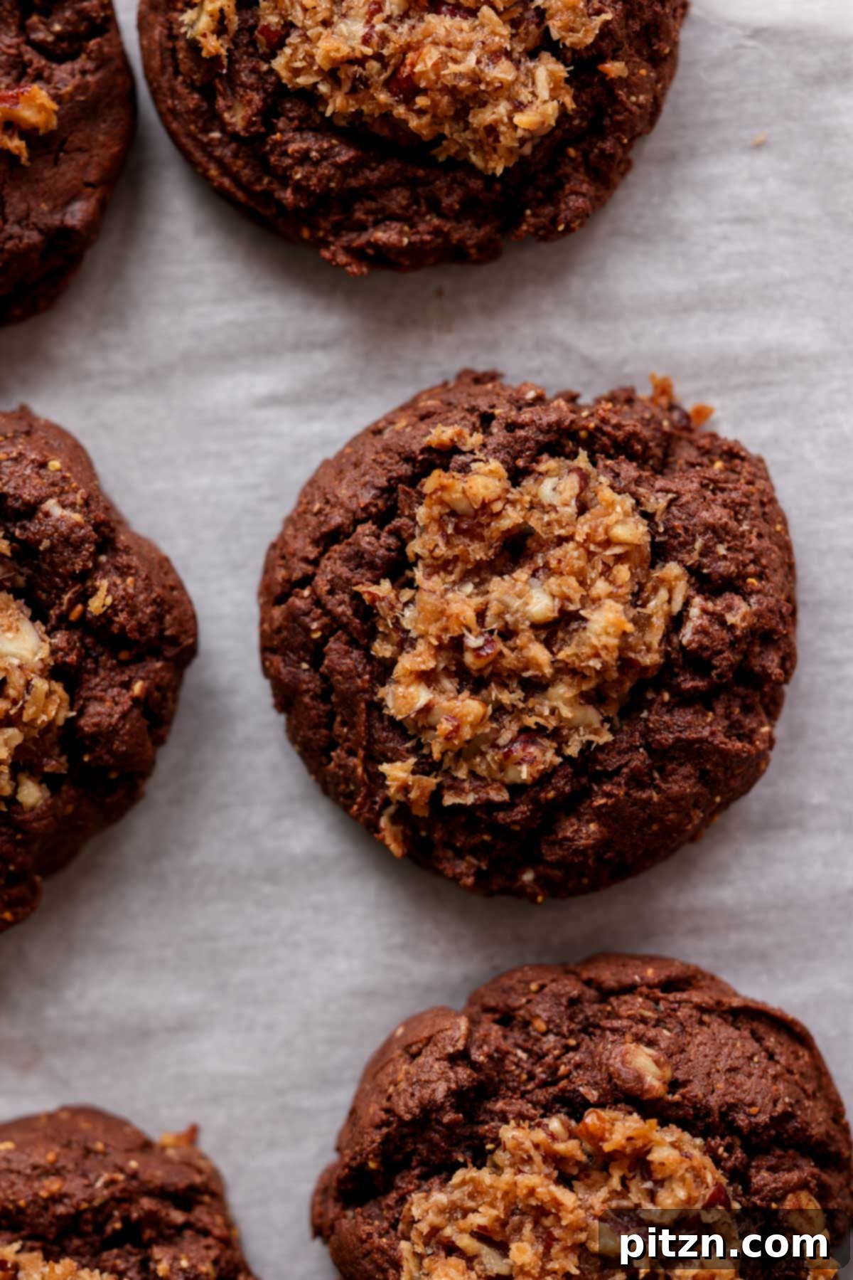 An overhead view of several vegan German chocolate cookies freshly baked and arranged on a baking sheet, ready to be devoured.
