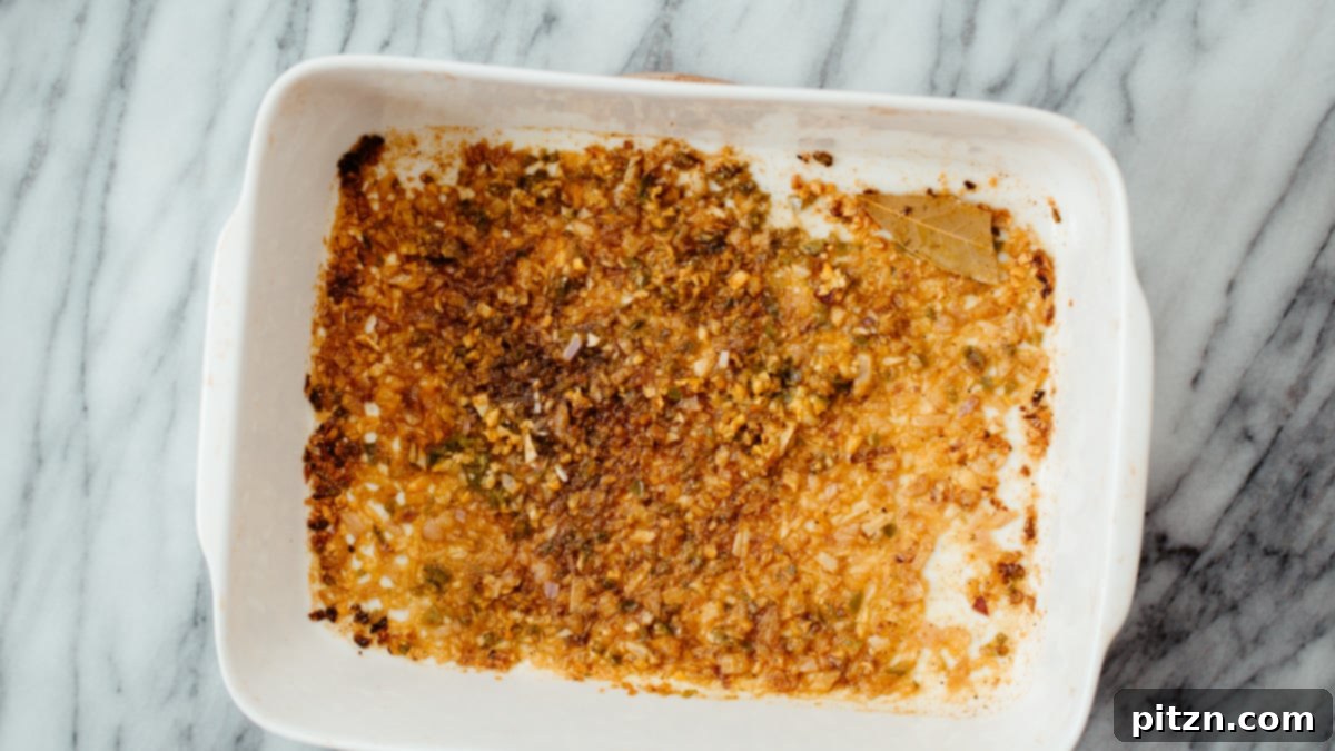 Overhead Roasted Spices An overhead shot of a casserole dish showcasing perfectly roasted spices, onions, and garlic, forming a fragrant base.
