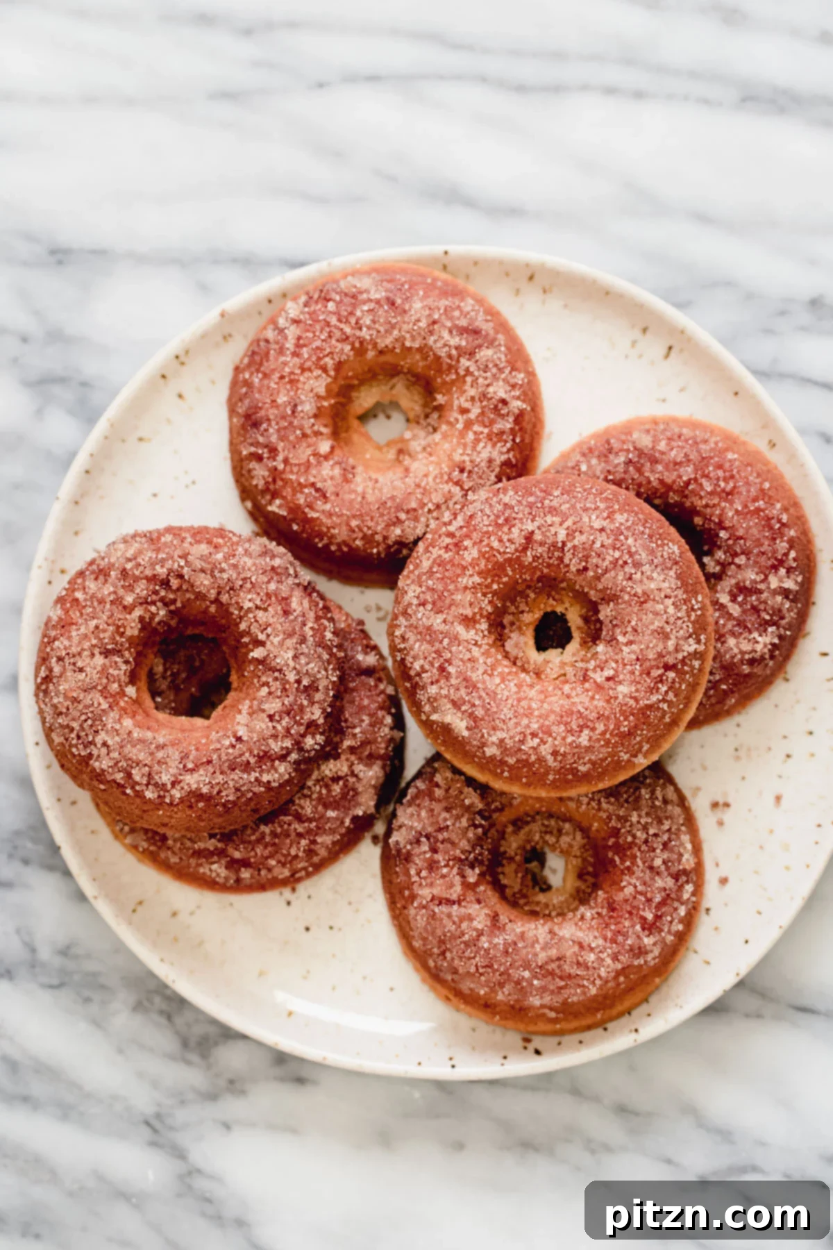 Plate of Cinnamon Sugar Gluten-Free Donuts A beautifully composed shot of a white plate piled high with fluffy, golden-brown gluten-free donuts, each generously coated in a shimmering layer of cinnamon sugar, ready to be enjoyed.
