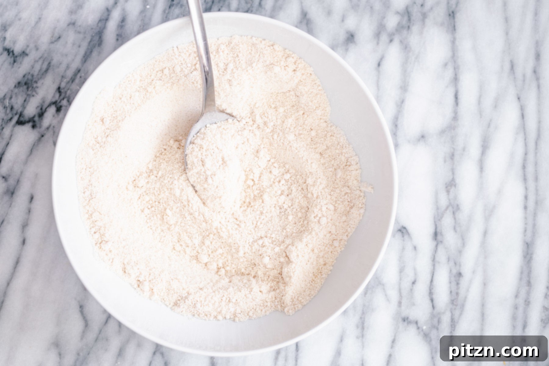 Dry Ingredients for Gluten-Free Donuts A white bowl holds the dry ingredients for gluten-free vanilla donuts, carefully mixed together to ensure an even distribution before the wet ingredients are added.