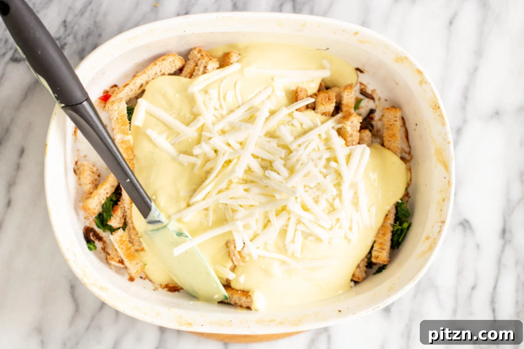 Vegan cheese on breakfast casserole A generous sprinkling of vegan cheese shreds being added on top of the vegan breakfast casserole, ready for baking to golden perfection.