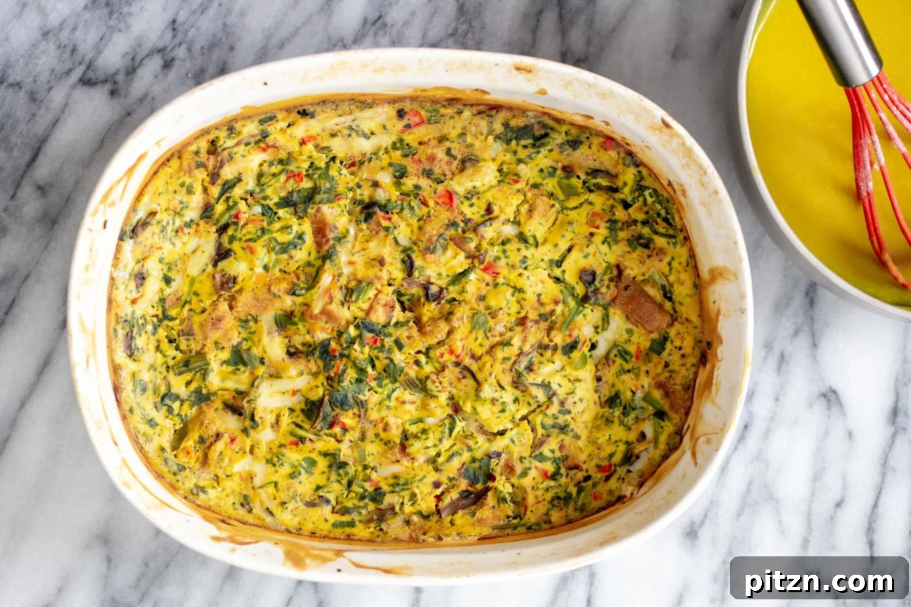 Vegan Eggs Benedict Breakfast Casserole 4 A beautifully baked vegan breakfast casserole, golden and bubbling, resting in a white ceramic baking dish, fresh out of the oven.