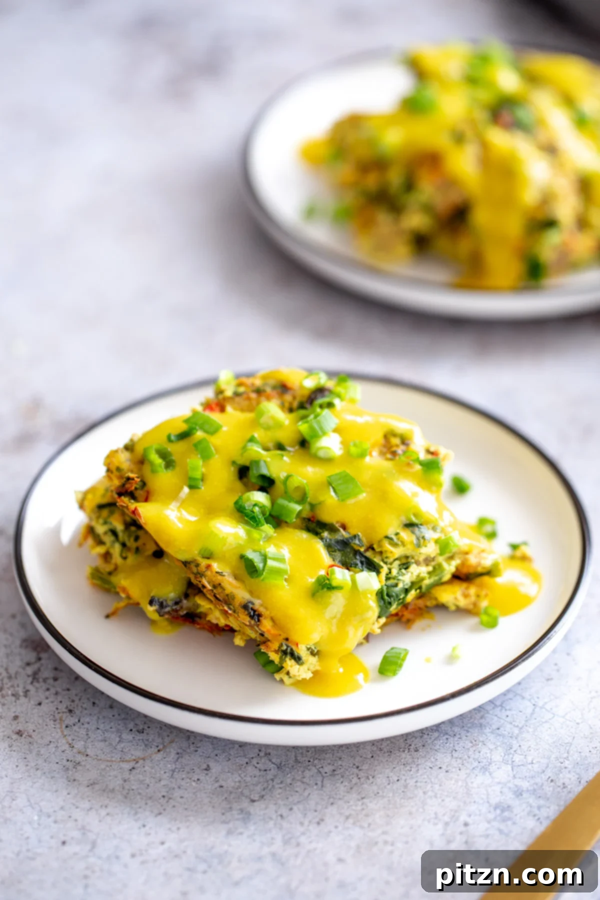 Vegan Breakfast Casserole serving A close-up, overhead shot of a single serving of the vegan breakfast casserole, elegantly presented and topped with creamy vegan hollandaise.