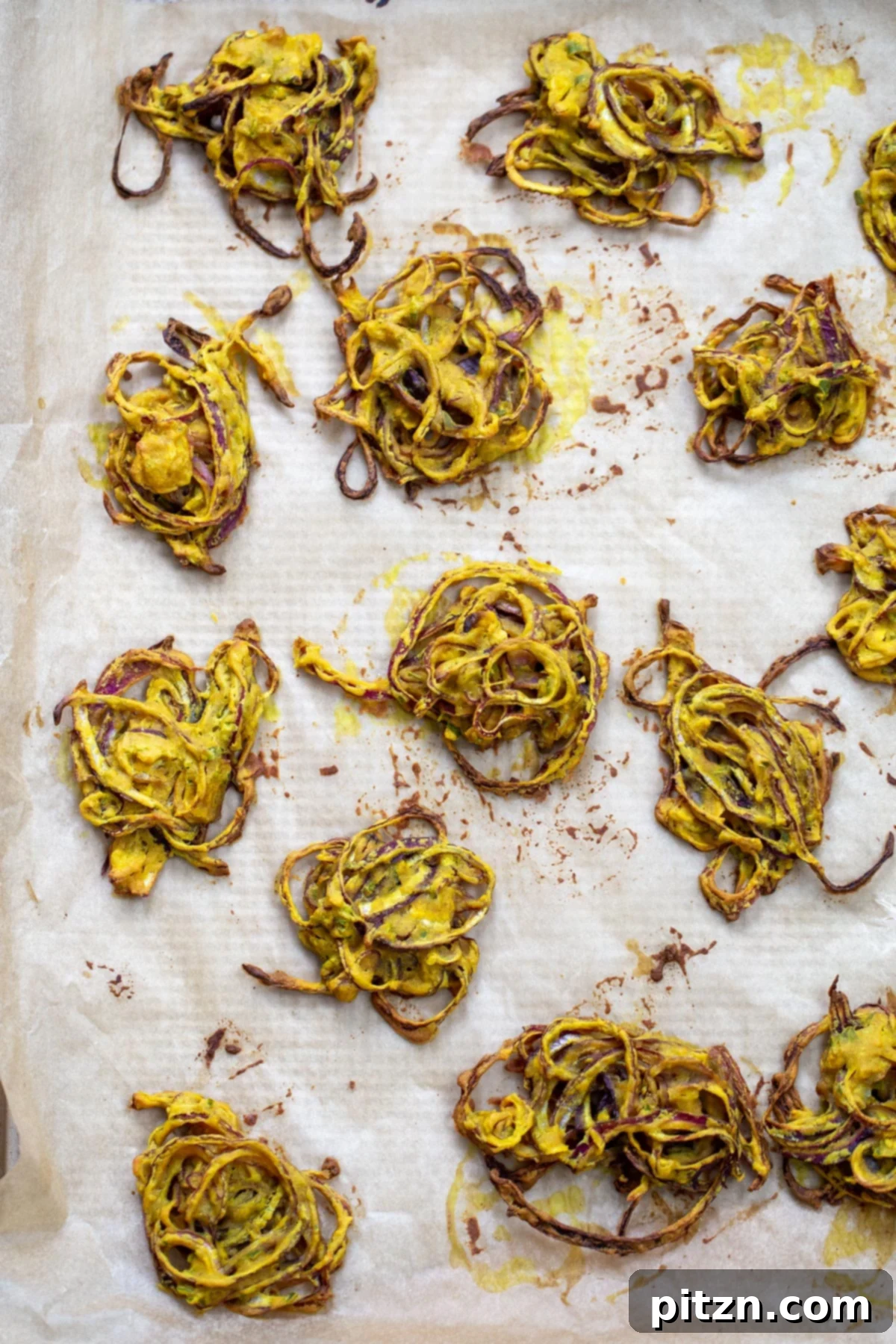 A baking sheet filled with freshly baked, golden-brown onion pakora, straight out of the oven. Each pakora looks perfectly crisp and ready to be served, highlighting the successful baking process.