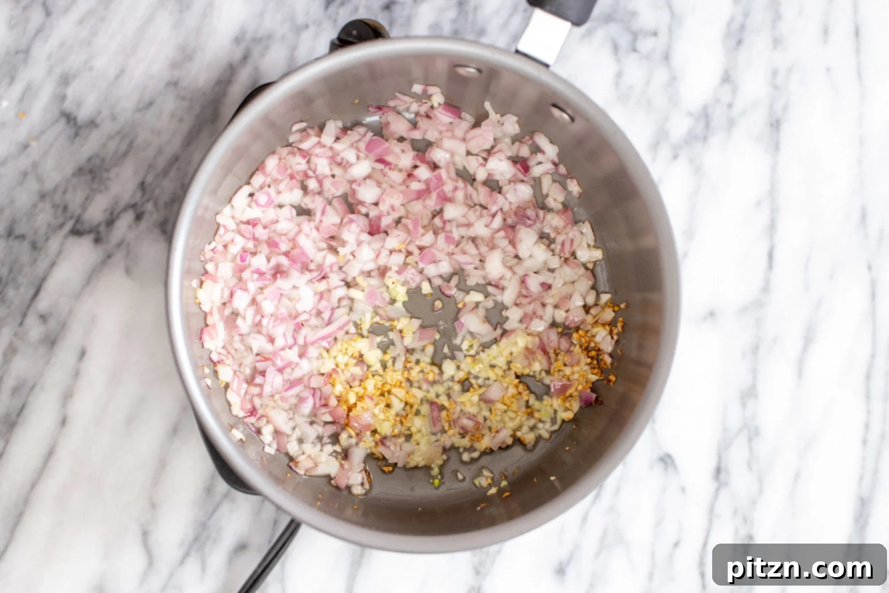 sautéing aromatics for vegan enchilada soup chopped onion, garlic and chile flakes being fried in a pot, starting the base of the vegan enchilada soup