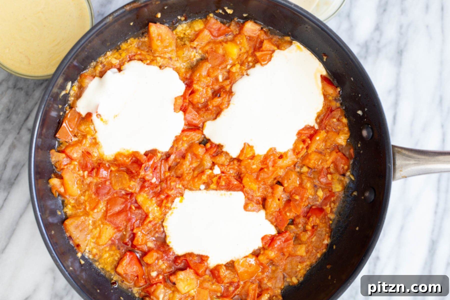 Vegan Tofu Shakshuka 10 tofu mix being added to pan with tomato sauce to make vegan eggs in purgatory