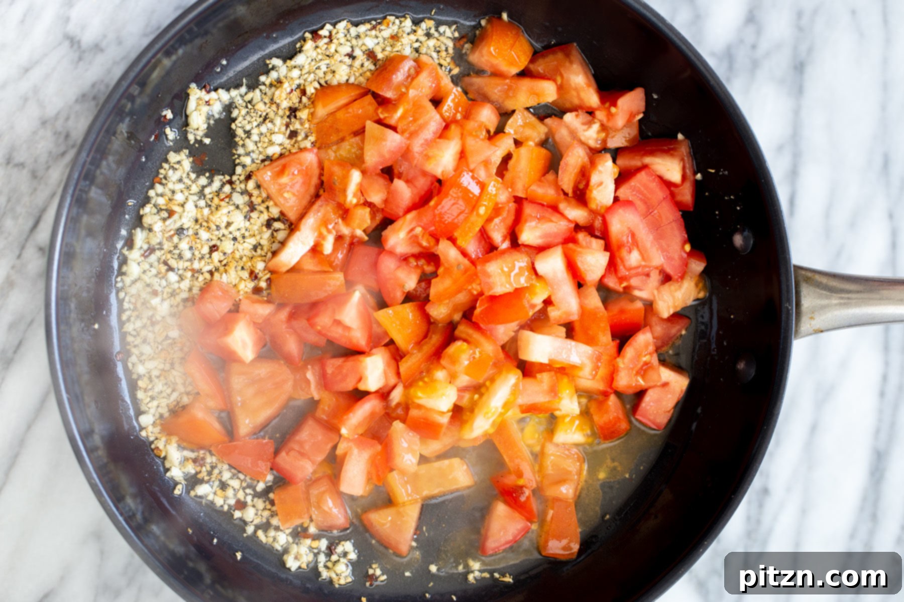 Vegan Tofu Shakshuka 8 fresh tomato chunks being added to sauteed garlic and red pepper to make vegan tomato sauce
