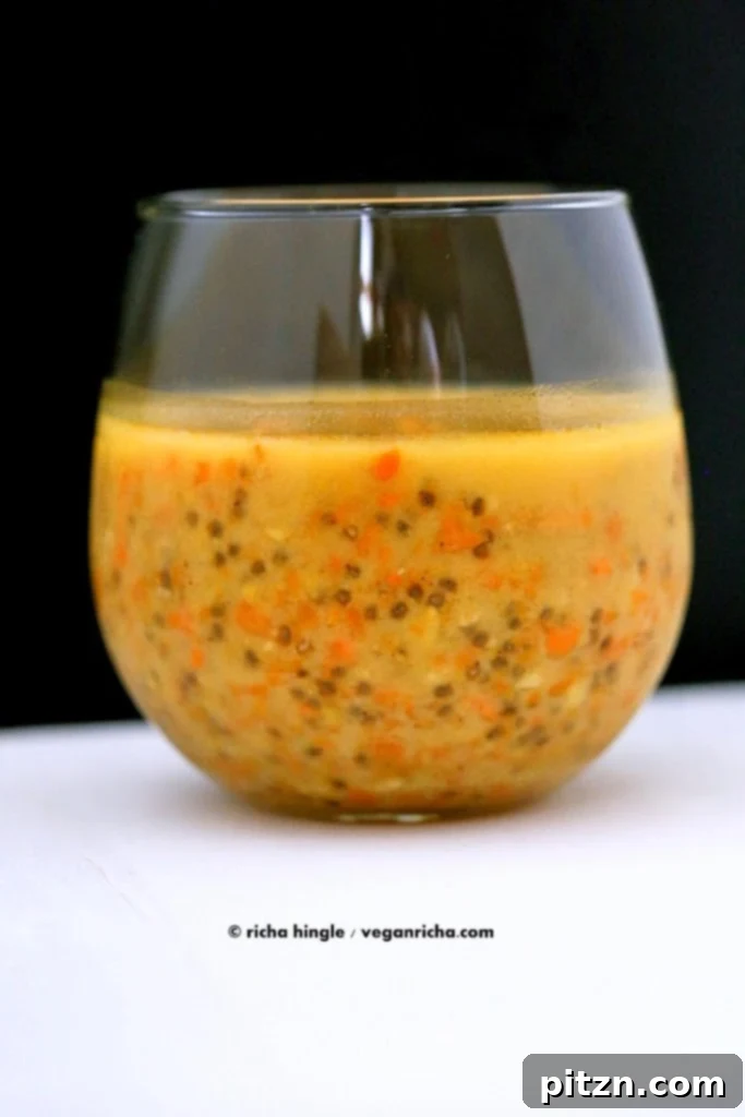 Close-up of a glass of Carrot Cake Chia Pudding, highlighting the creamy texture and small pieces of roasted carrot, topped with walnuts.
