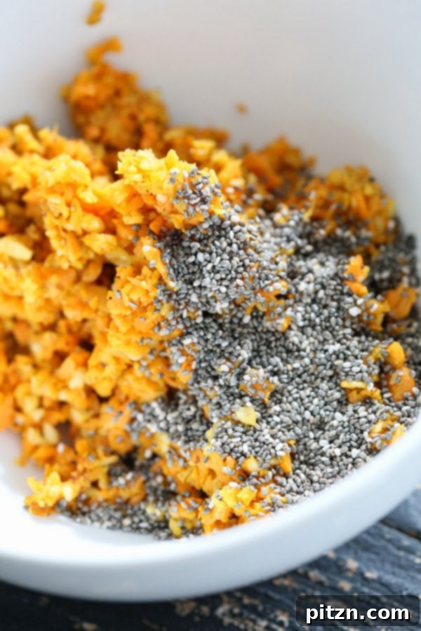 Close-up of chopped carrots and oats being roasted with spices and maple syrup in a non-stick pan.