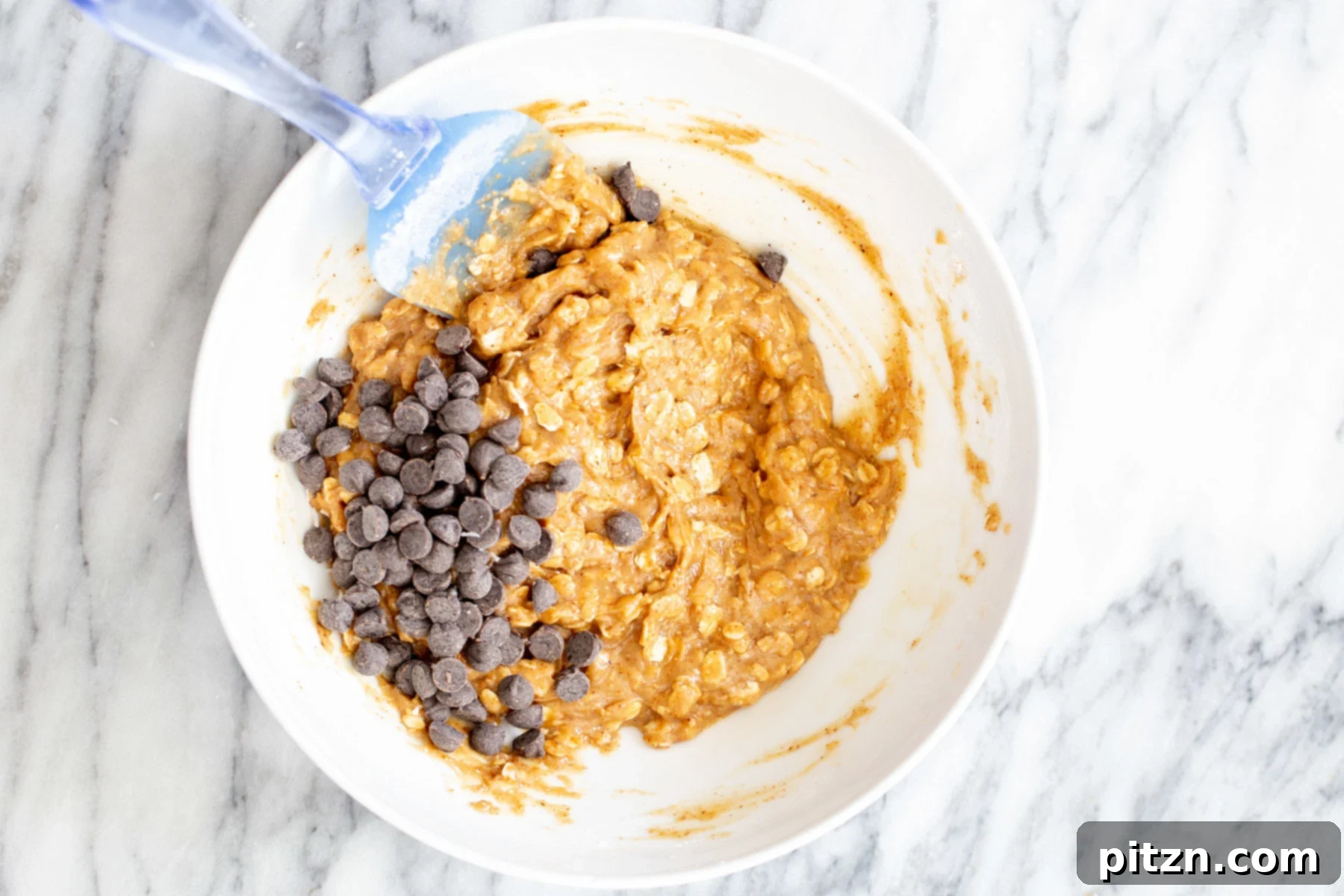 chocolate chips being added to vegan oatmeal bar base 