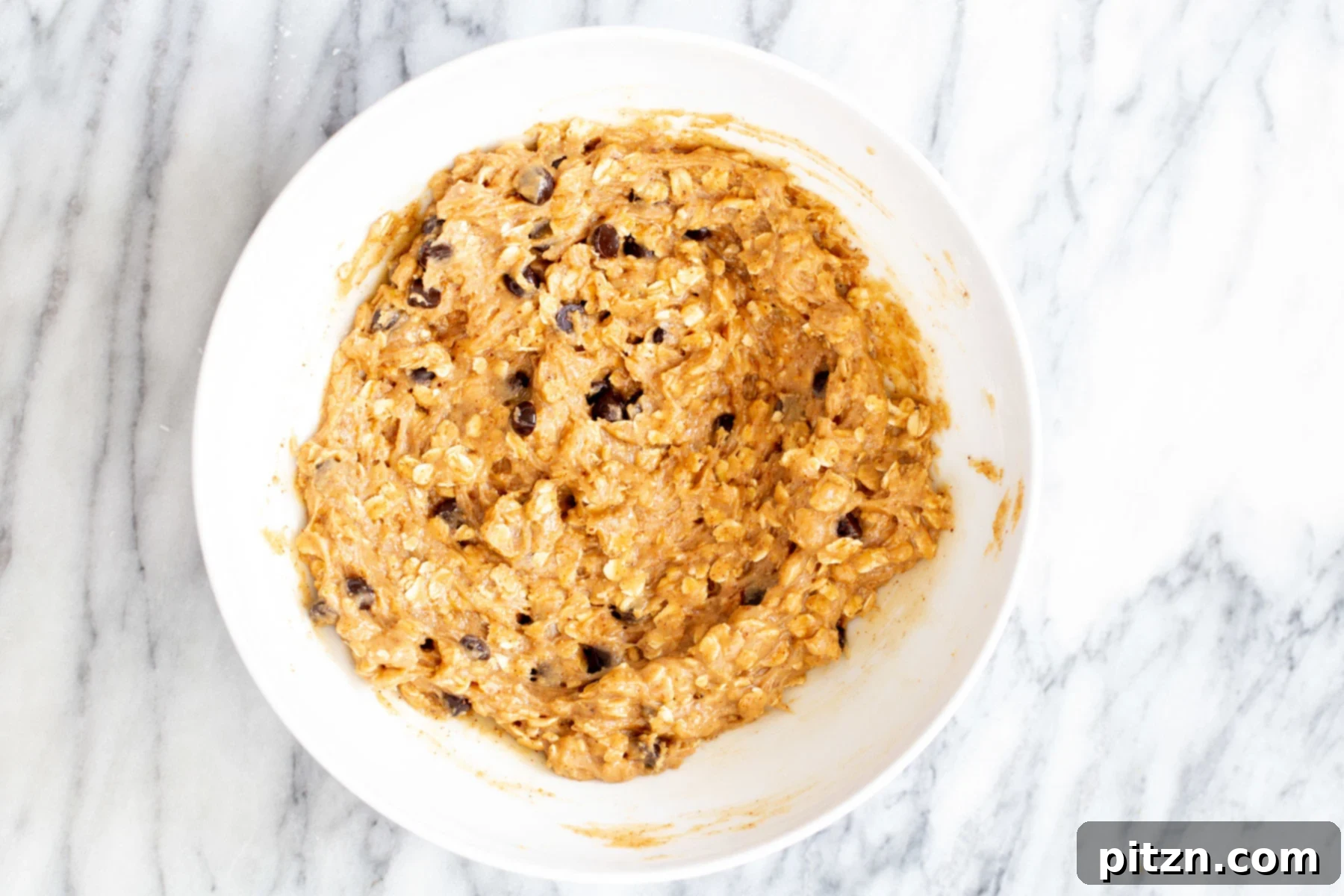 vegan carmelita oatmeal batter with chocolate chips in a mixing bowl 