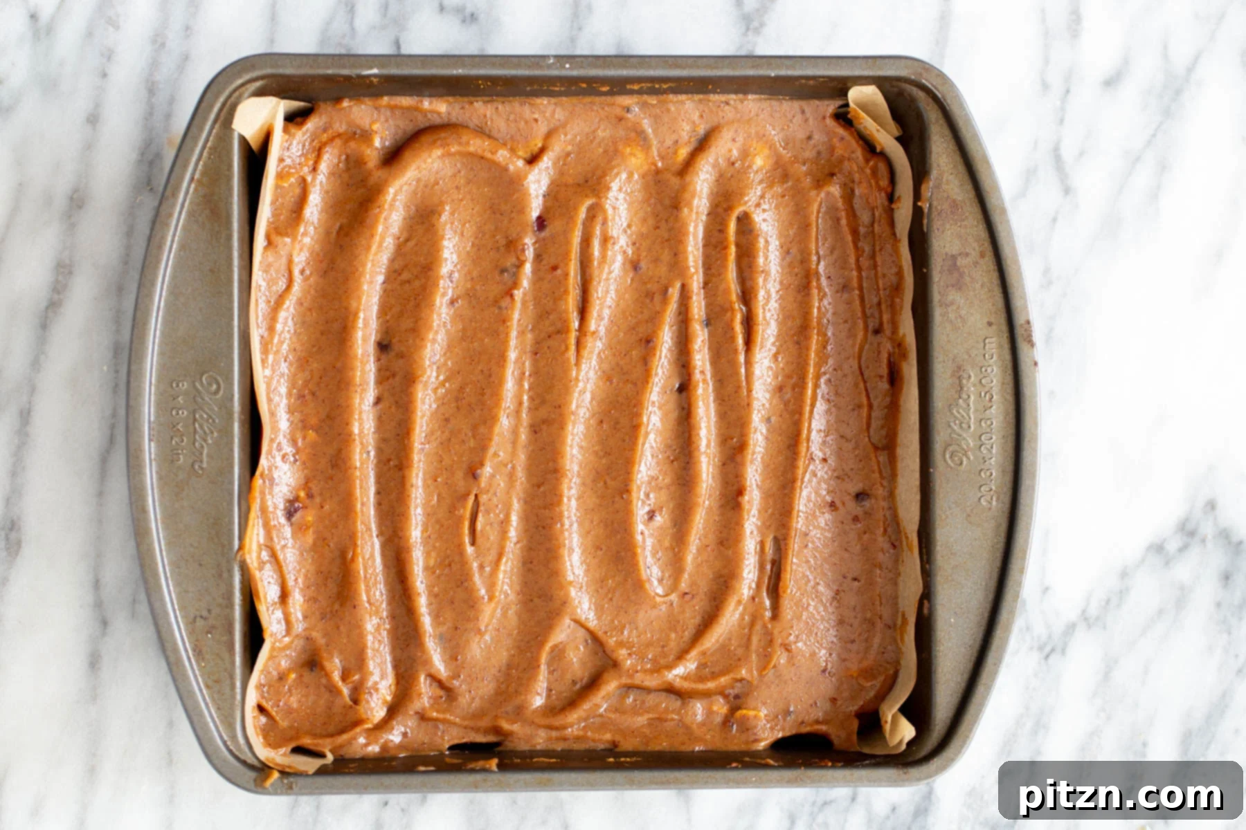 vegan date caramel being spread on oatmeal batter to make vegan date caramel oatmeal bars 
