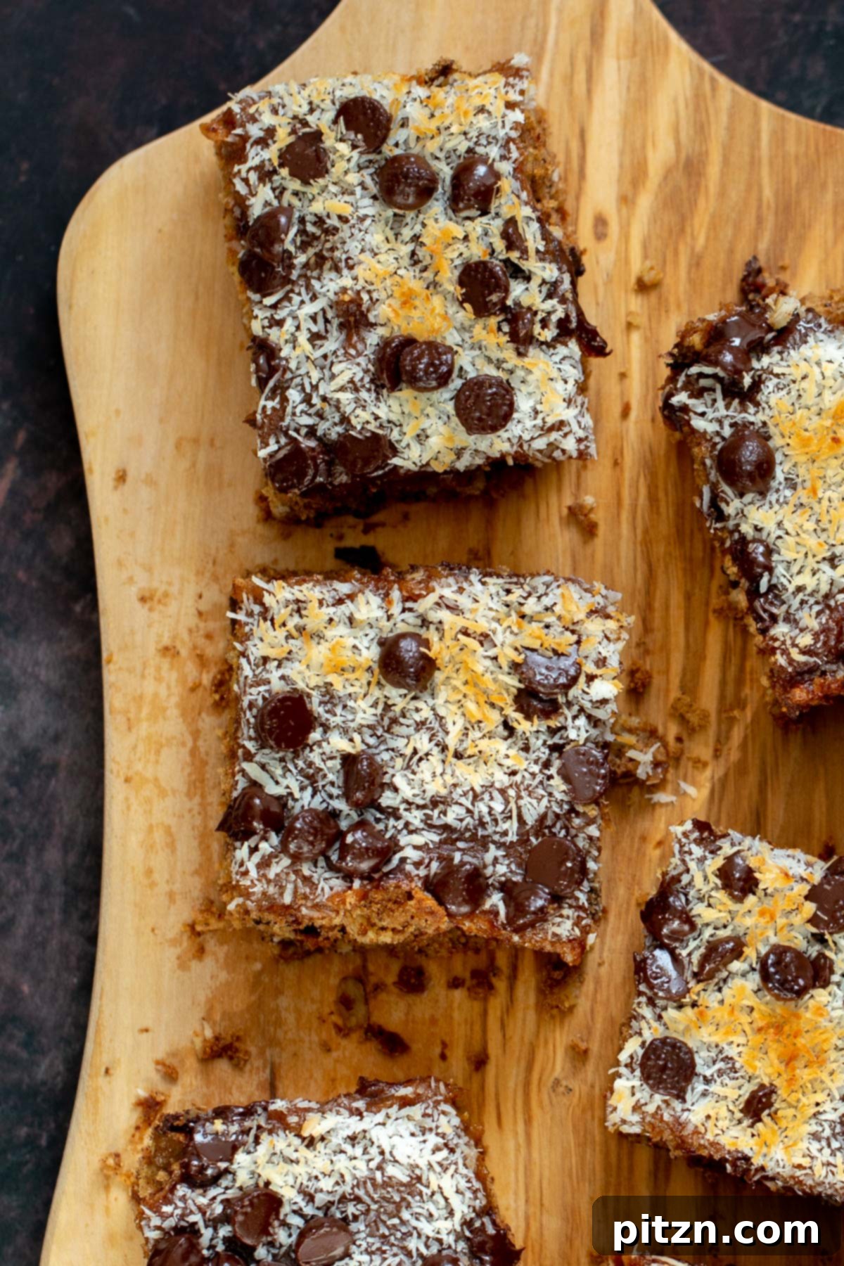 vegan oatmeal date caramel snack bars topped with shredded coconut and chocolate chips on a cutting board 