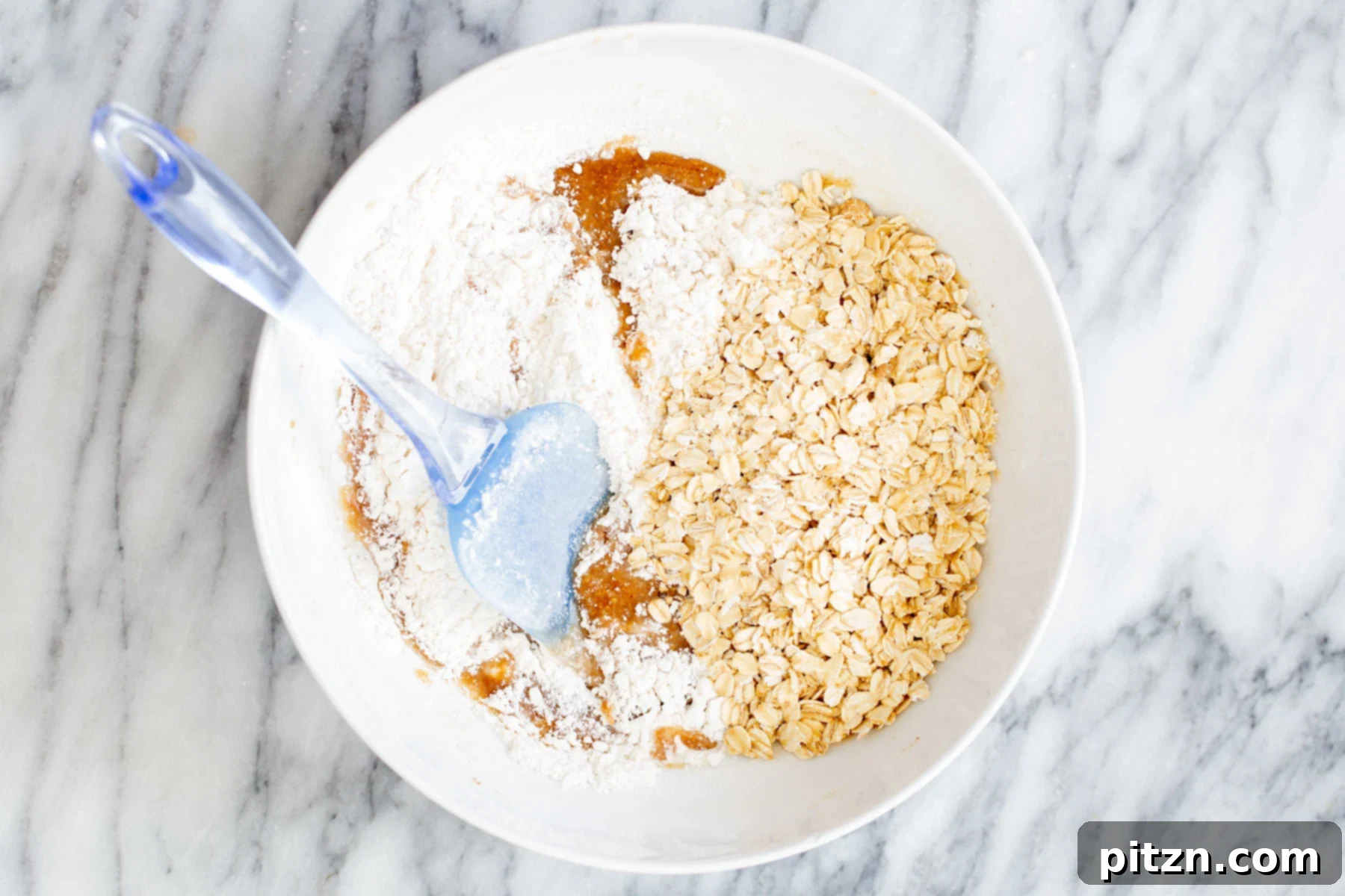 oats and flour being added to wet dough to make vegan oatmeal bars 