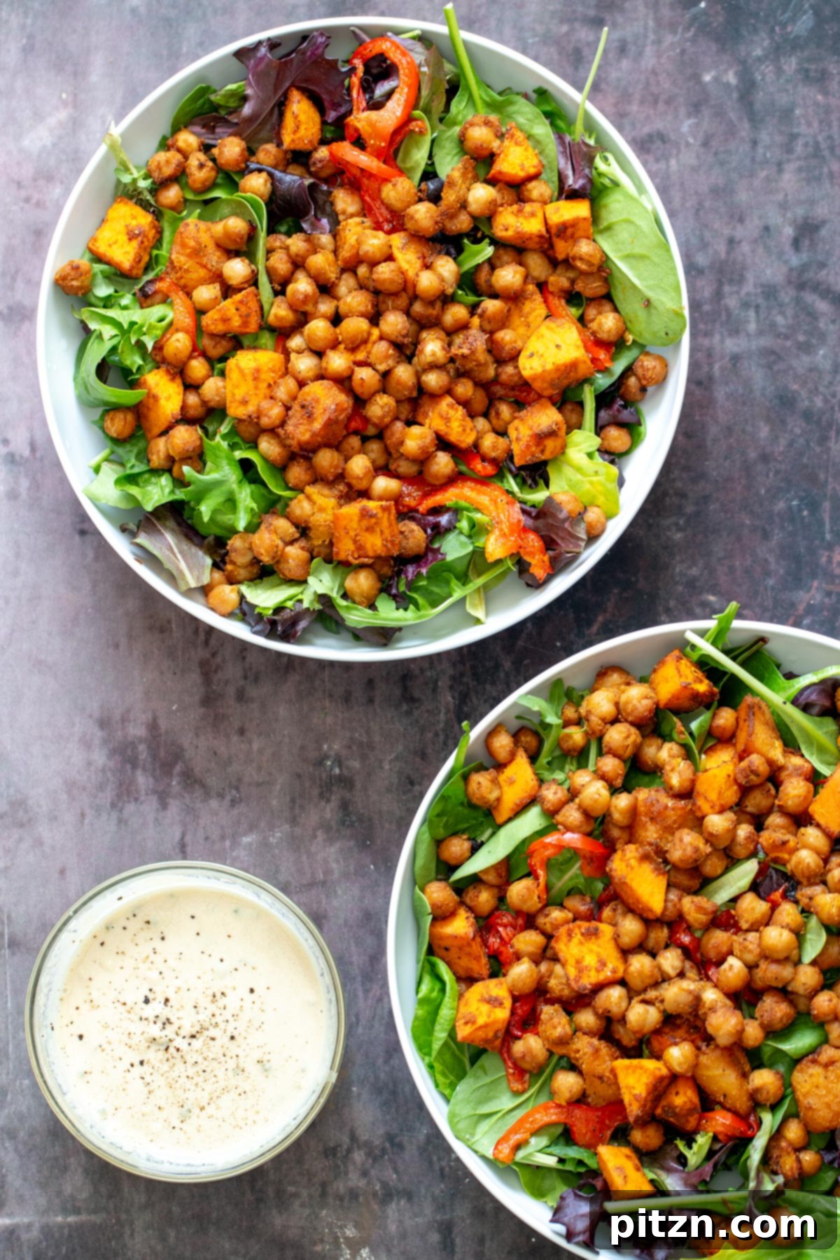 Two beautiful bowls of sweet potato chickpea salad with a small side dish of creamy tahini sauce, ready to be served.