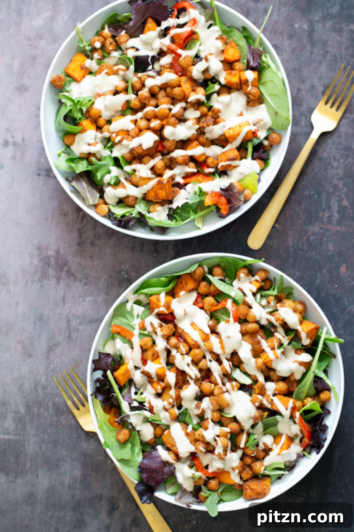Two beautifully plated white bowls of sweet potato chickpea salad, generously drizzled with creamy tahini dressing, showcasing a complete and appetizing meal.
