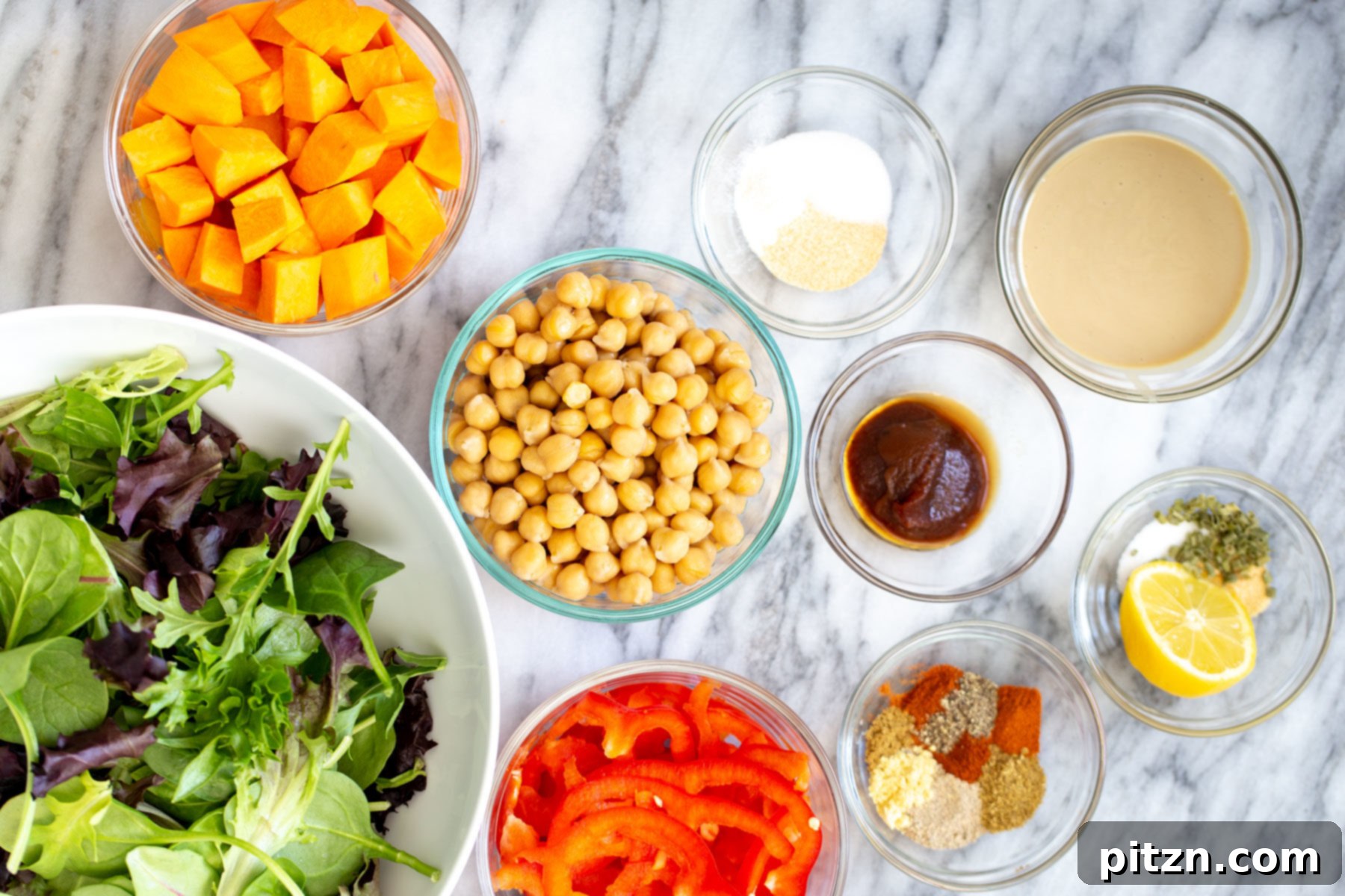 Assorted ingredients laid out for making a healthy sweet potato chickpea salad bowl, including sweet potatoes, chickpeas, bell peppers, spices, and tahini.