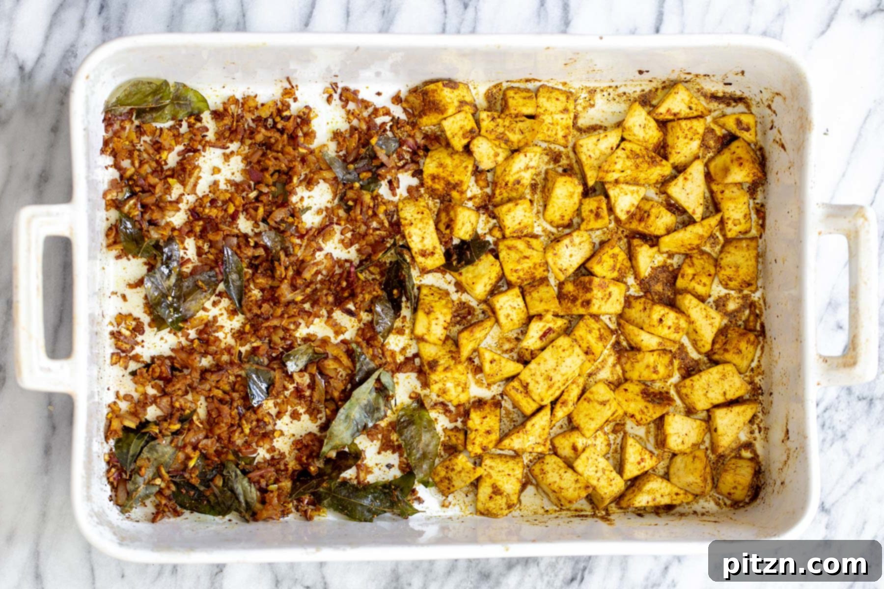 A casserole dish with expertly spiced baked tofu on one side and beautifully sautéed onions on the other, forming the base of the curry.